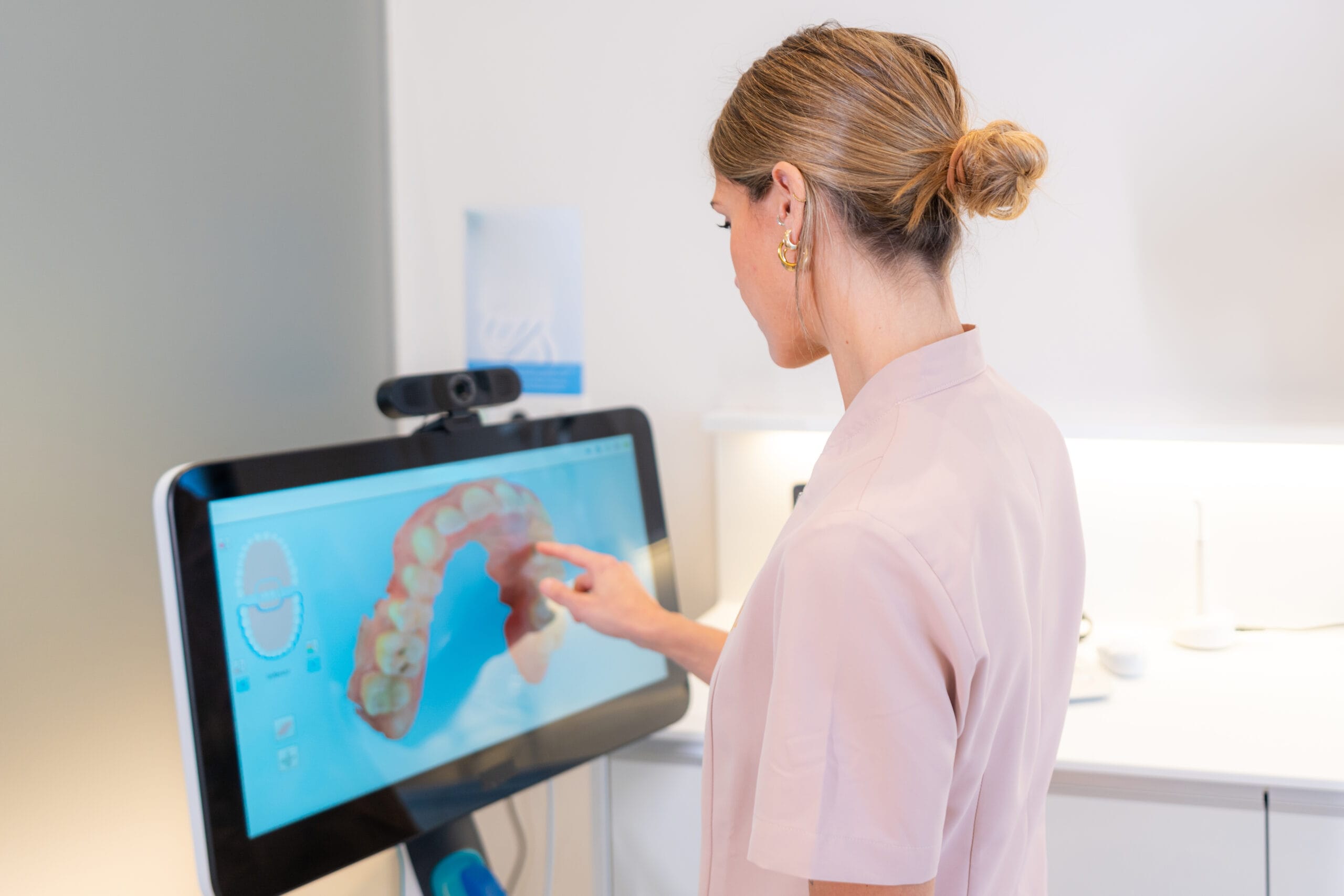Dentist looking at 3D x-ray on client's monitor in modern dental clinic