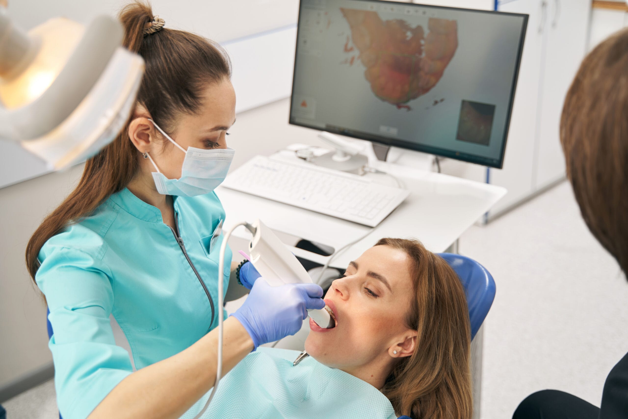 Dentist scanning woman teeth with dental intraoral 3D scanner Happy woman curing teeth in dentistry.