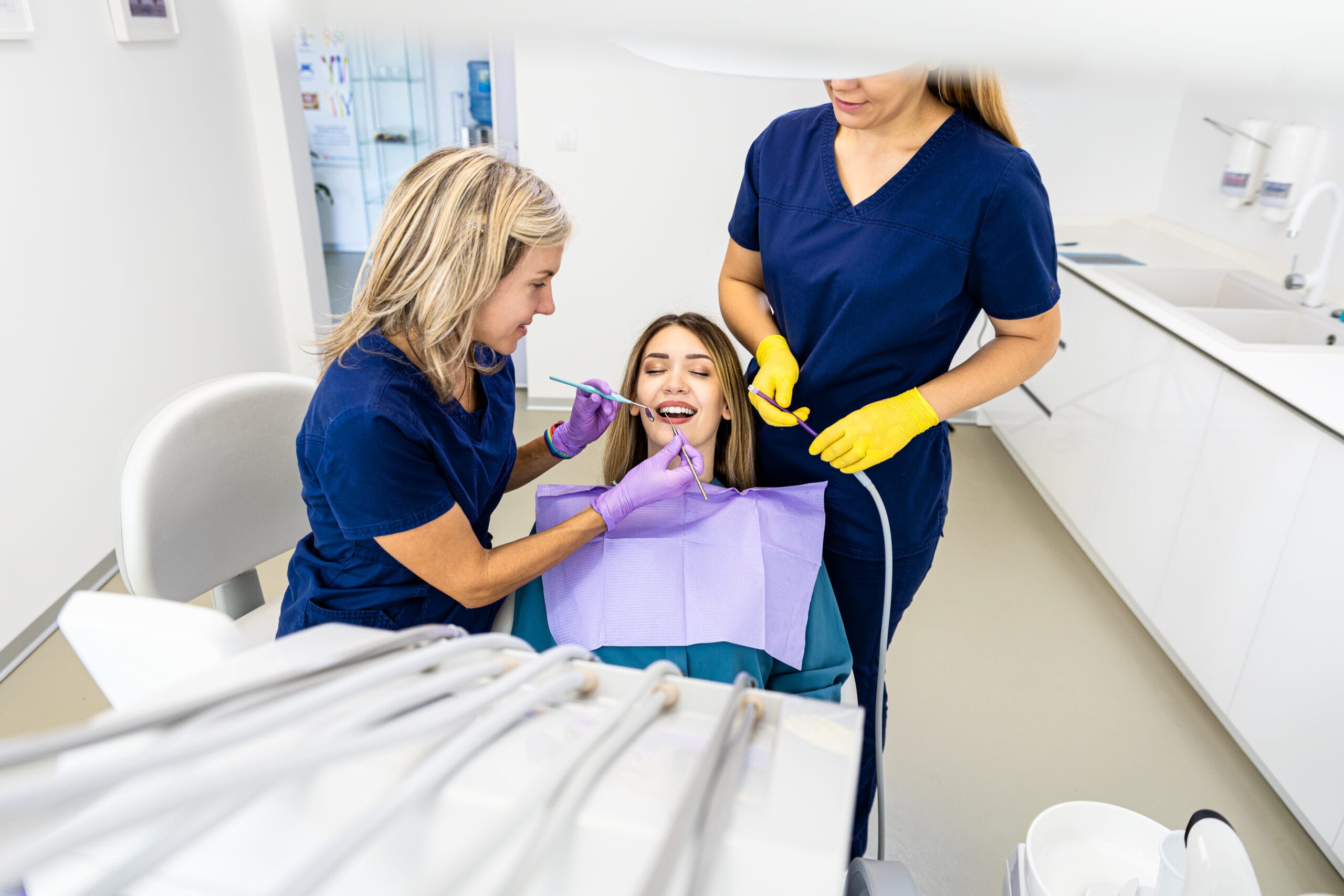 Female dentist with assistant working in dental clinic examining