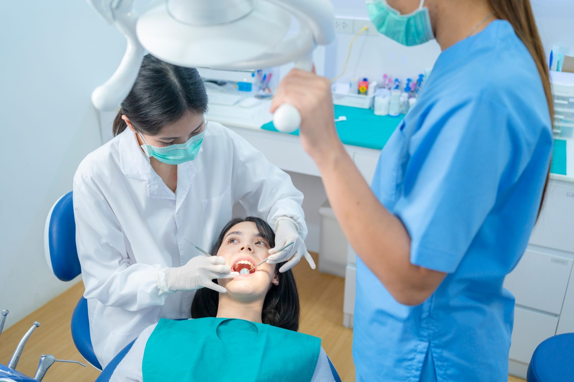 Asian female dentist checking or examining tooth of young girl patient lying on dental chair. Asian female dentist checking or examining tooth of young girl patient lying on dental chair.