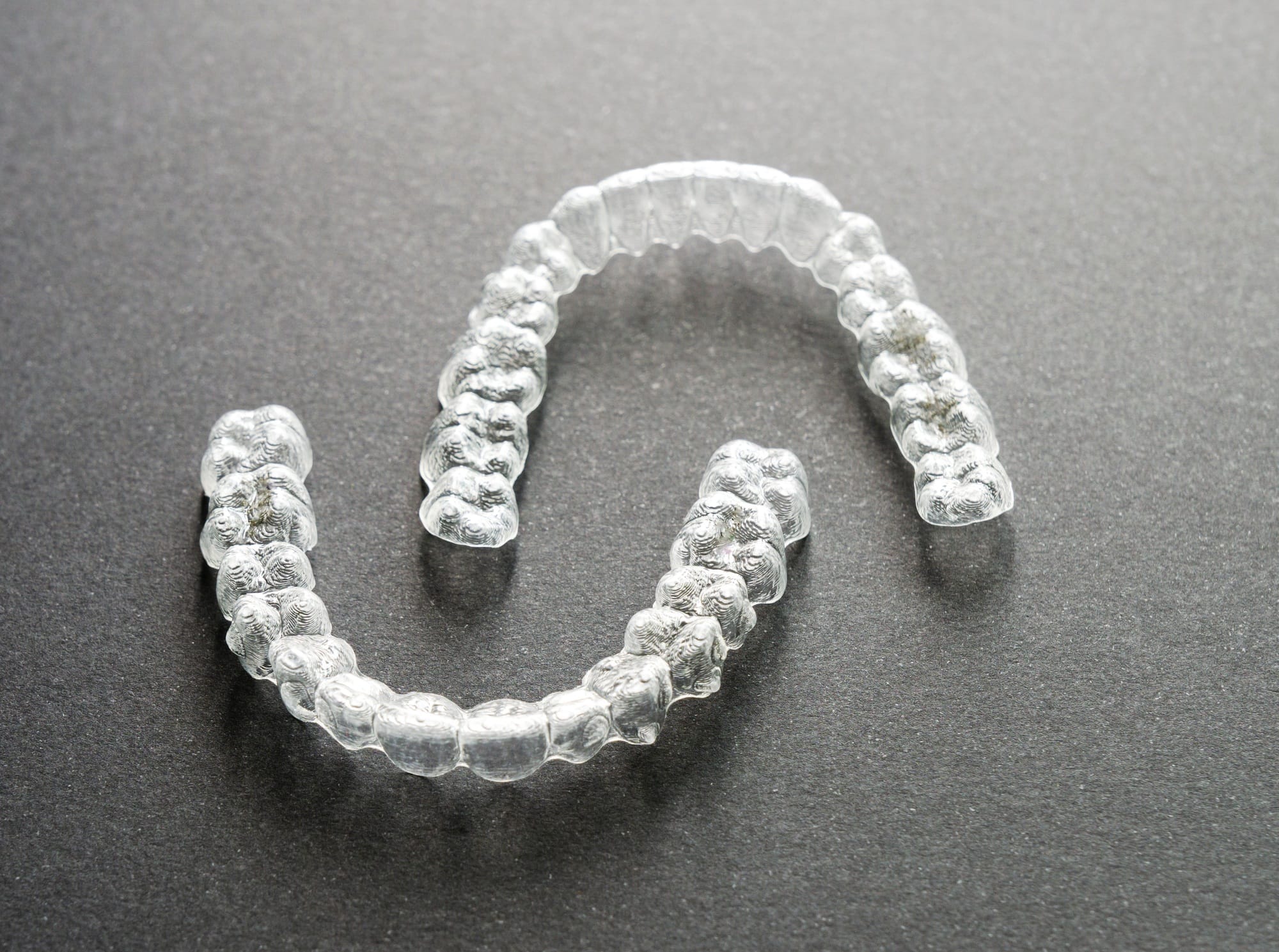 Close-up of clear orthodontic aligners splints on a gray surface