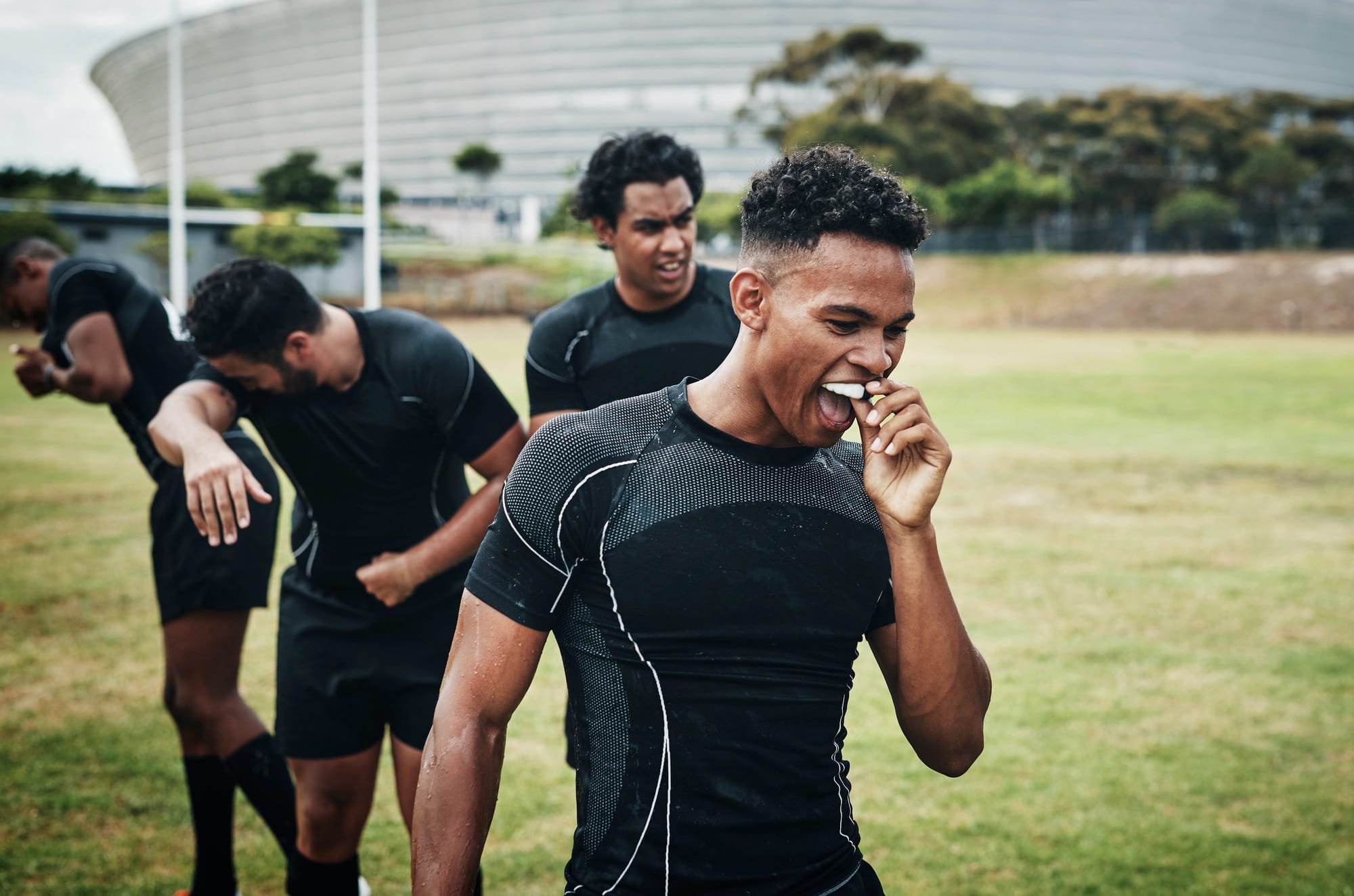 Cropped shot of a handsome young rugby player removing his mouthguard during half-time on the field Cropped shot of a handsome young rugby player removing his mouthguard during half-time on the field