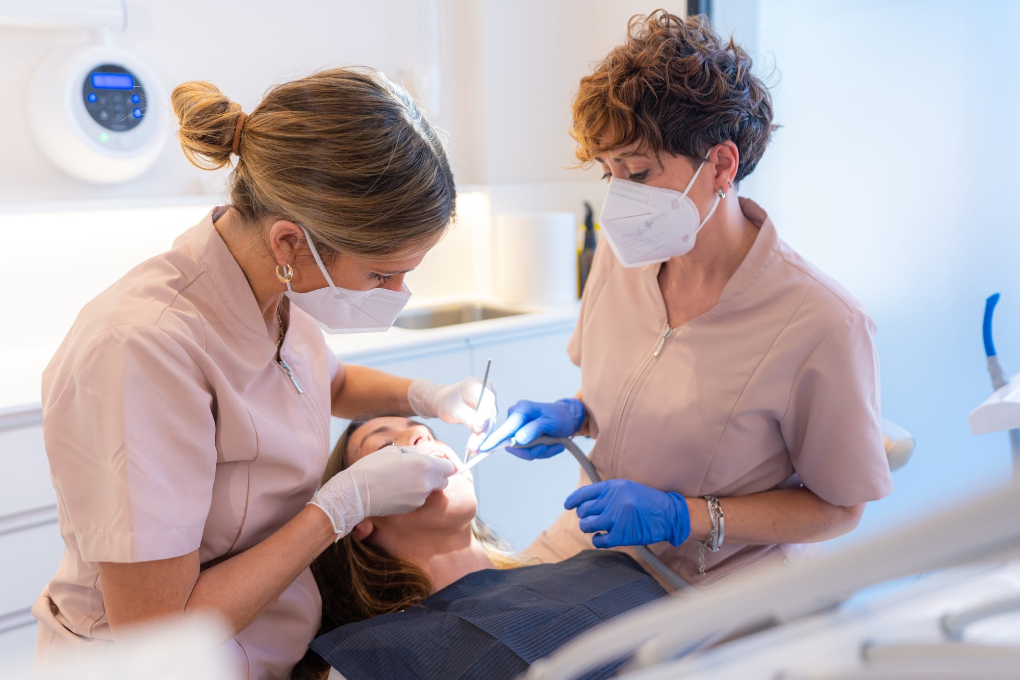 Dentist and assistant performing a filling on a tooth for a client in the modern dental clinic Dentist and assistant performing a filling on a tooth for a client in the modern dental clinic