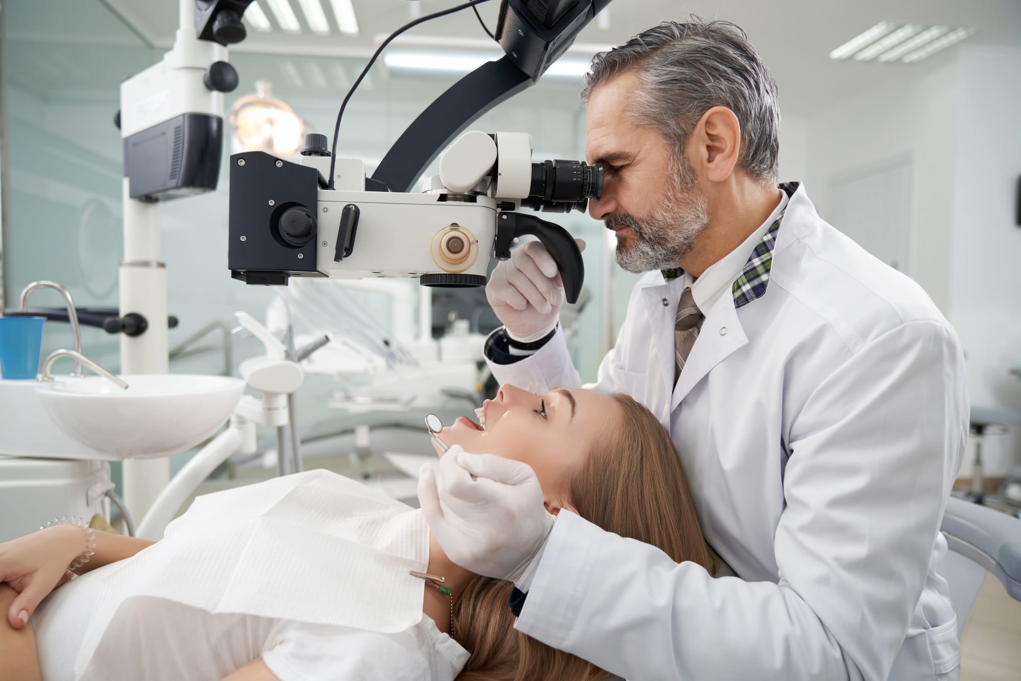 Dentist using dental microscope for examination Dentist using dental microscope for examination