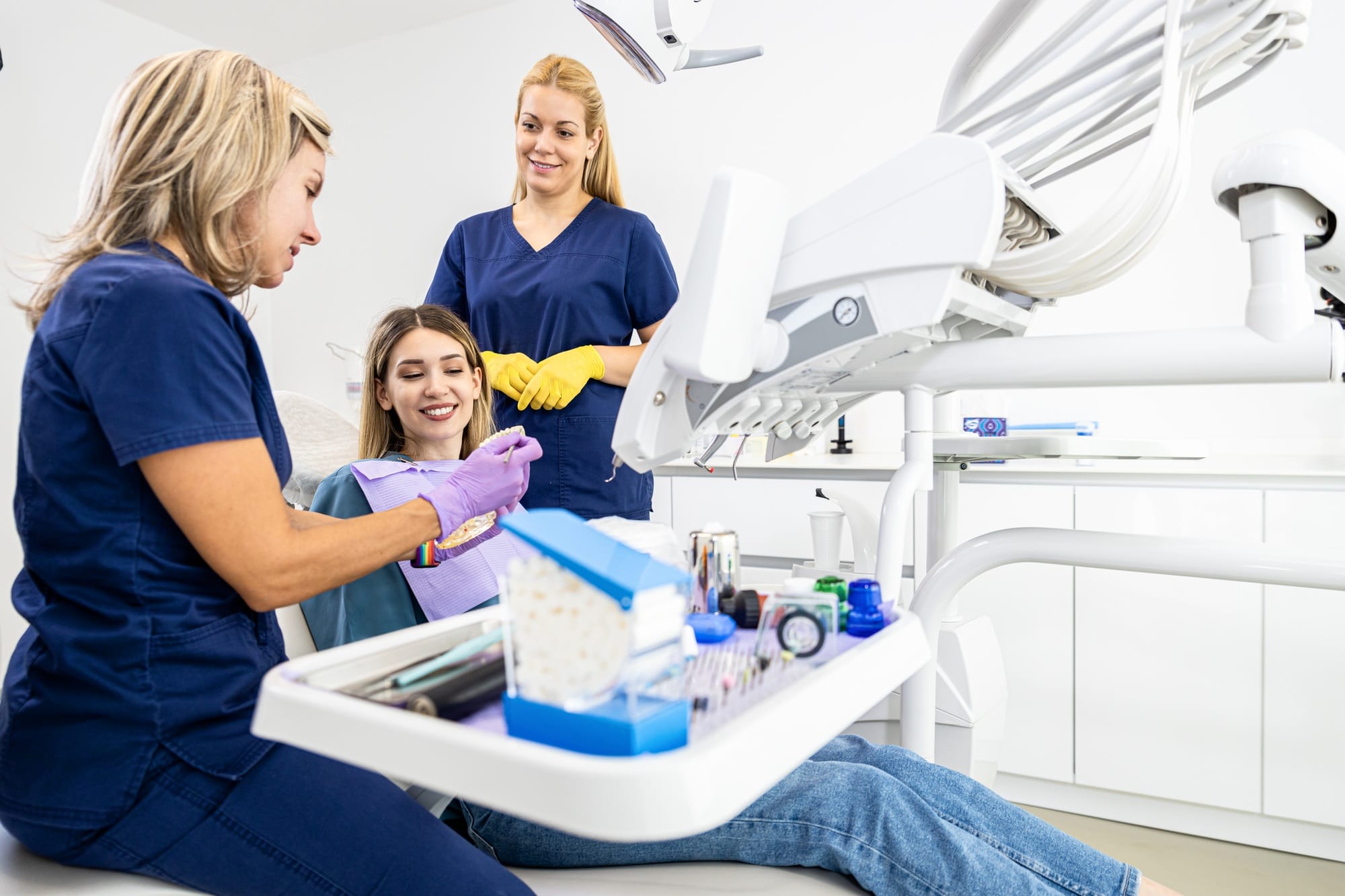 Female dentist with assistant working in dental clinic examining patient teeth. Female dentist with assistant working in dental clinic examining patient teeth.