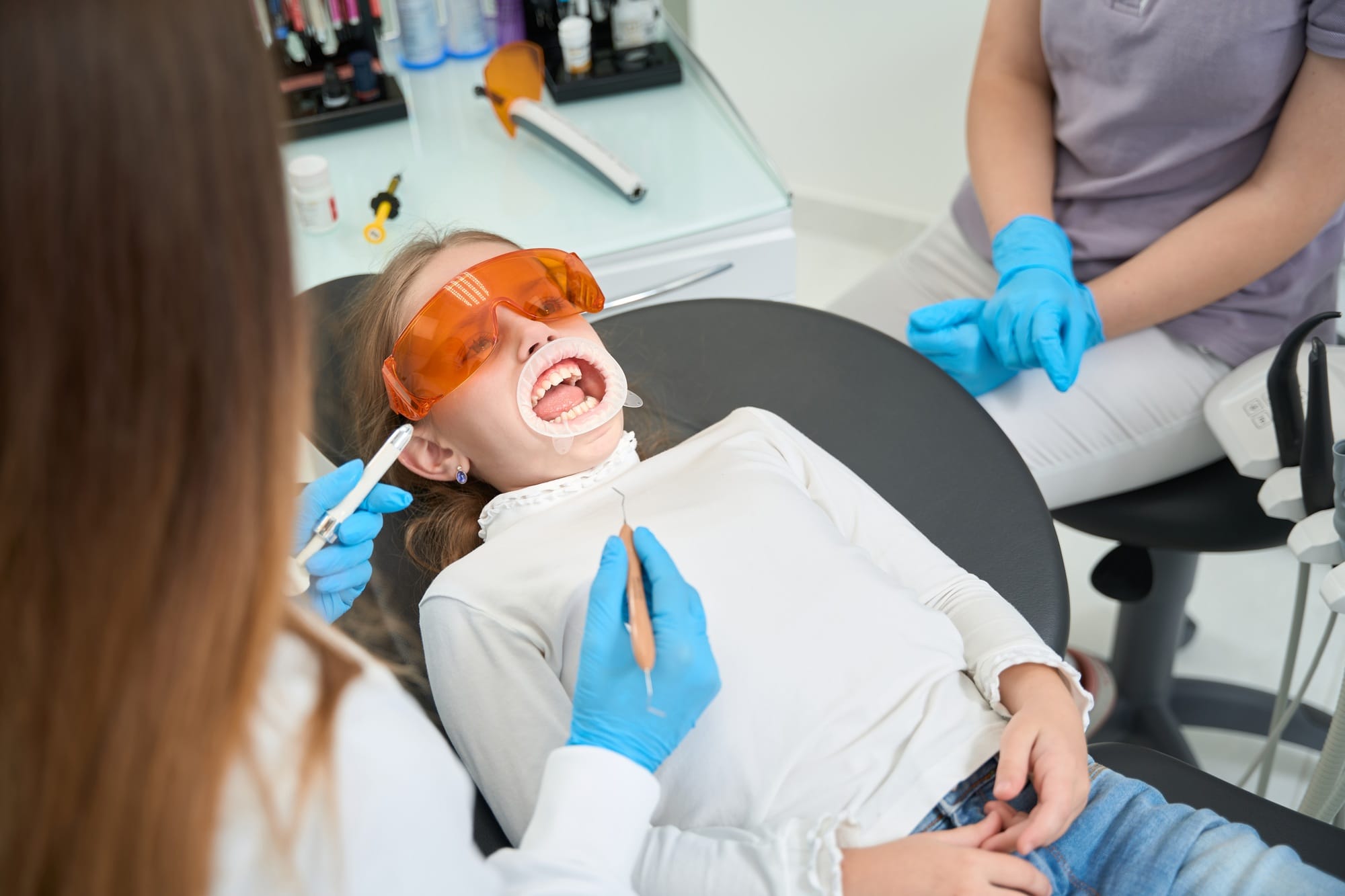 Pre-teen girl surrounded by dental staff before teeth examination Pre-teen girl surrounded by dental staff before teeth examination