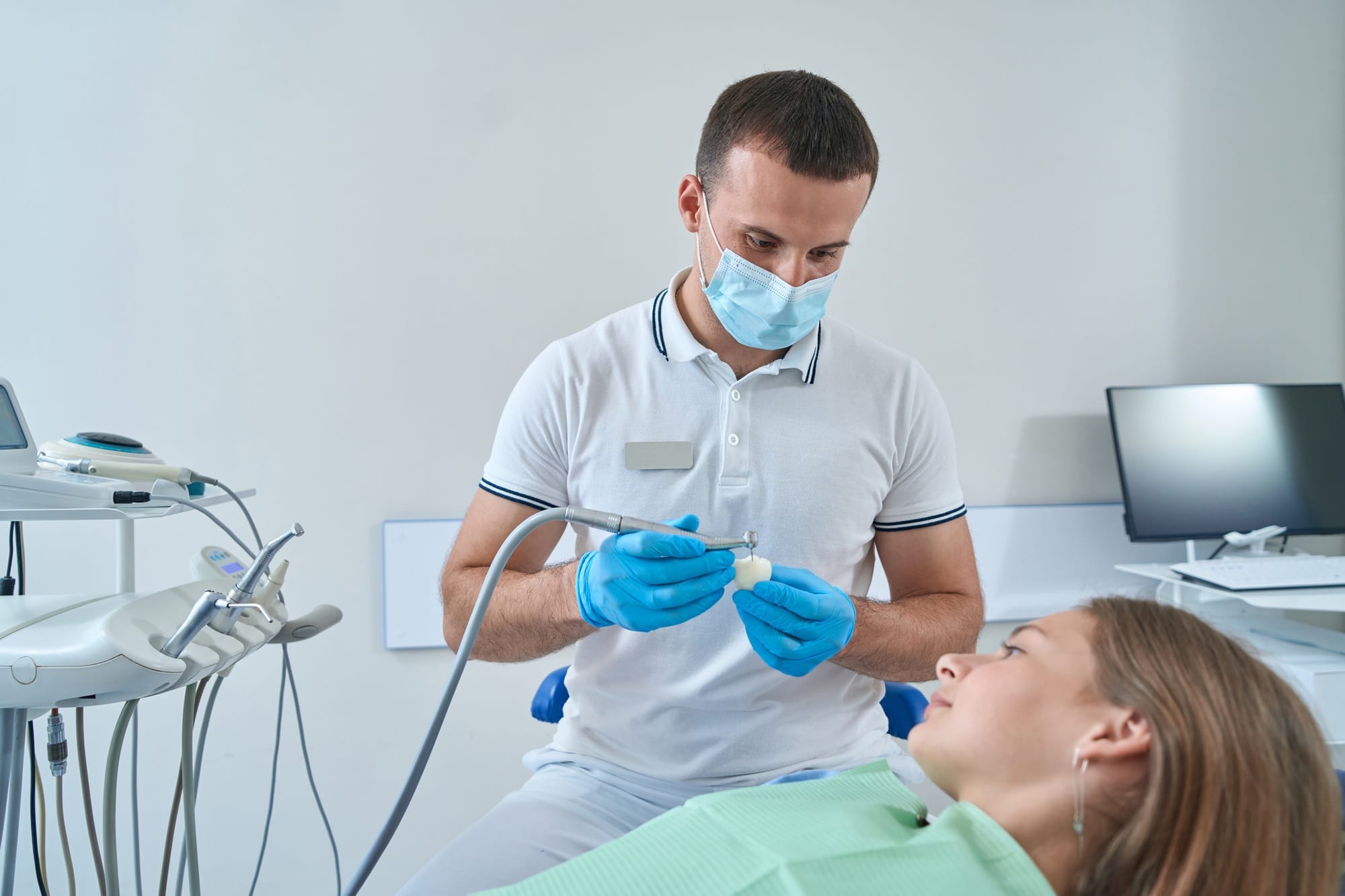 Serious focused pedodontist performing tooth restoration procedure Serious focused pedodontist performing tooth restoration procedure