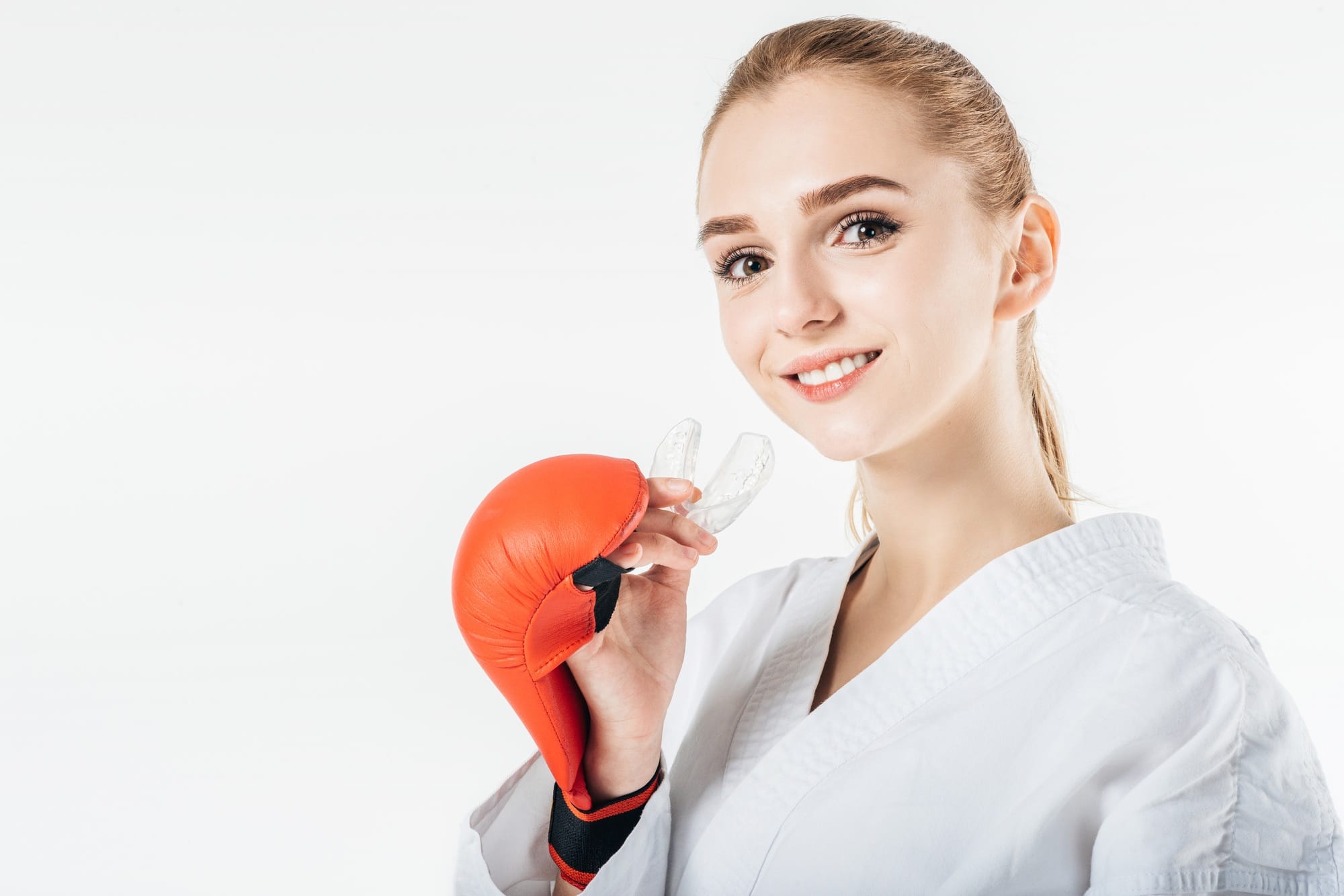 smiling female karate fighter holding mouthguard isolated on white smiling female karate fighter holding mouthguard isolated on white