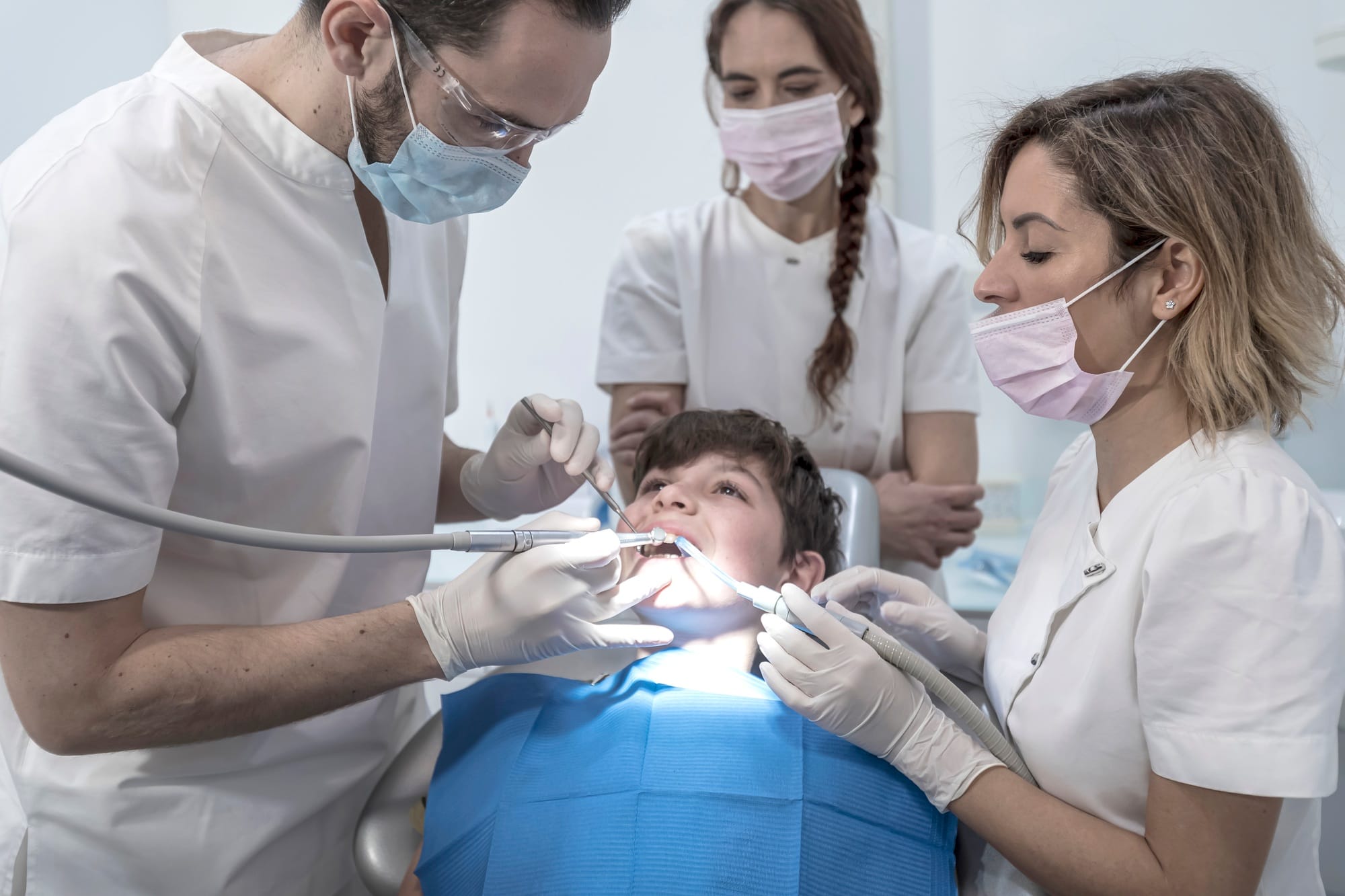 Team of dentists treating a young boy for orthodontics in the dentist's clinic Team of dentists treating a young boy for orthodontics in the dentist's clinic