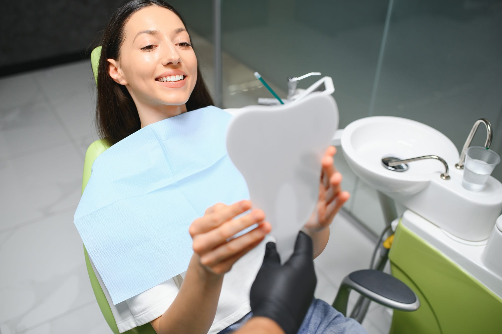 The girl smiles in dentistry. In the hands of the mirror