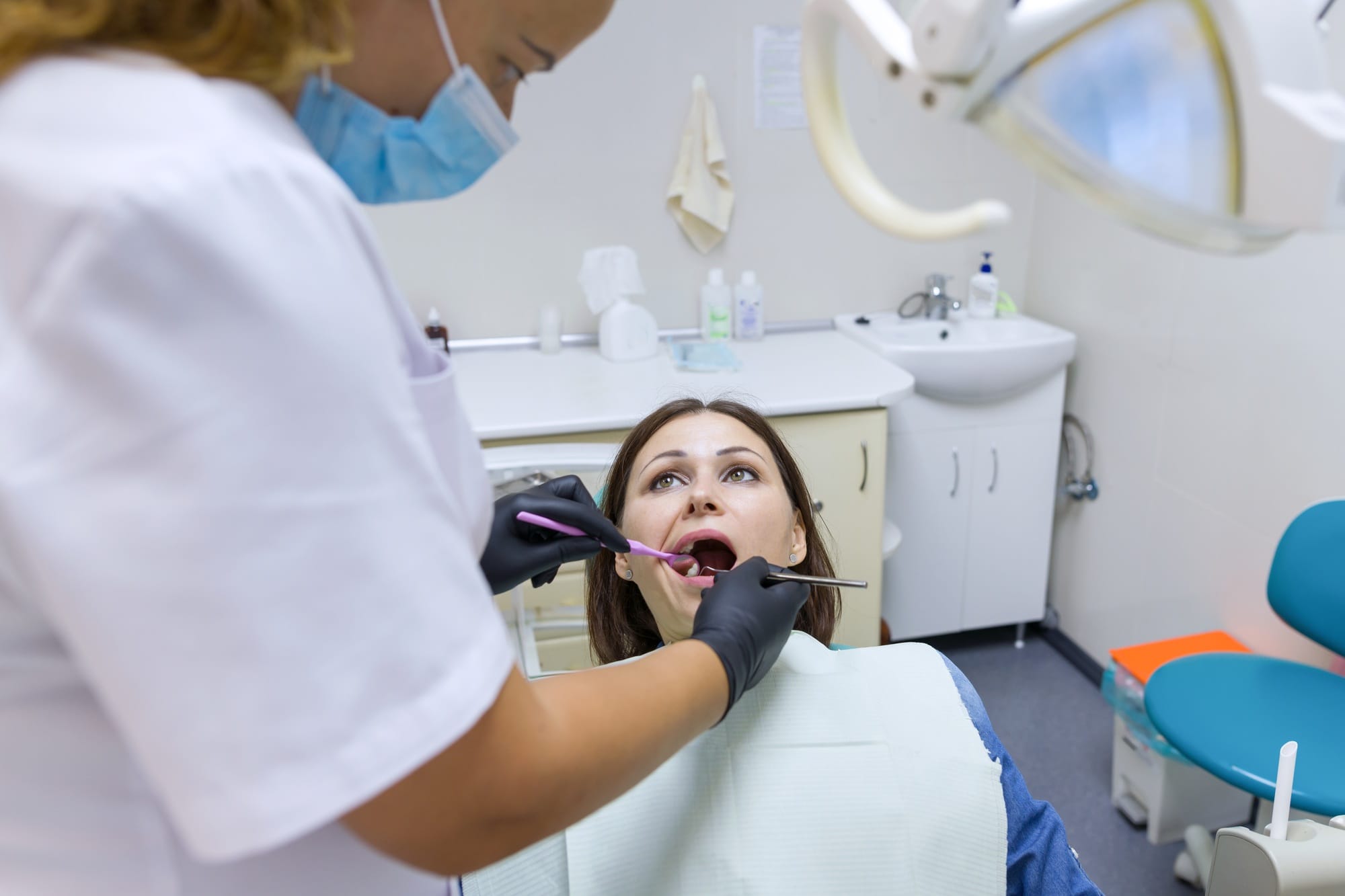 Adult female dentist treating patient woman teeth. Medicine, dentistry and healthcare concept