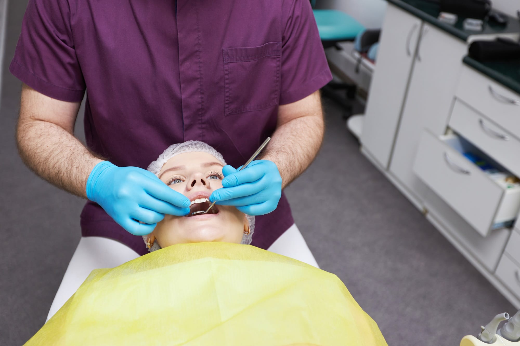 Close-up hands of a male doctor dentist hygienist examining for cavities and gum disease Close-up hands of a male doctor dentist hygienist examining for cavities and gum disease