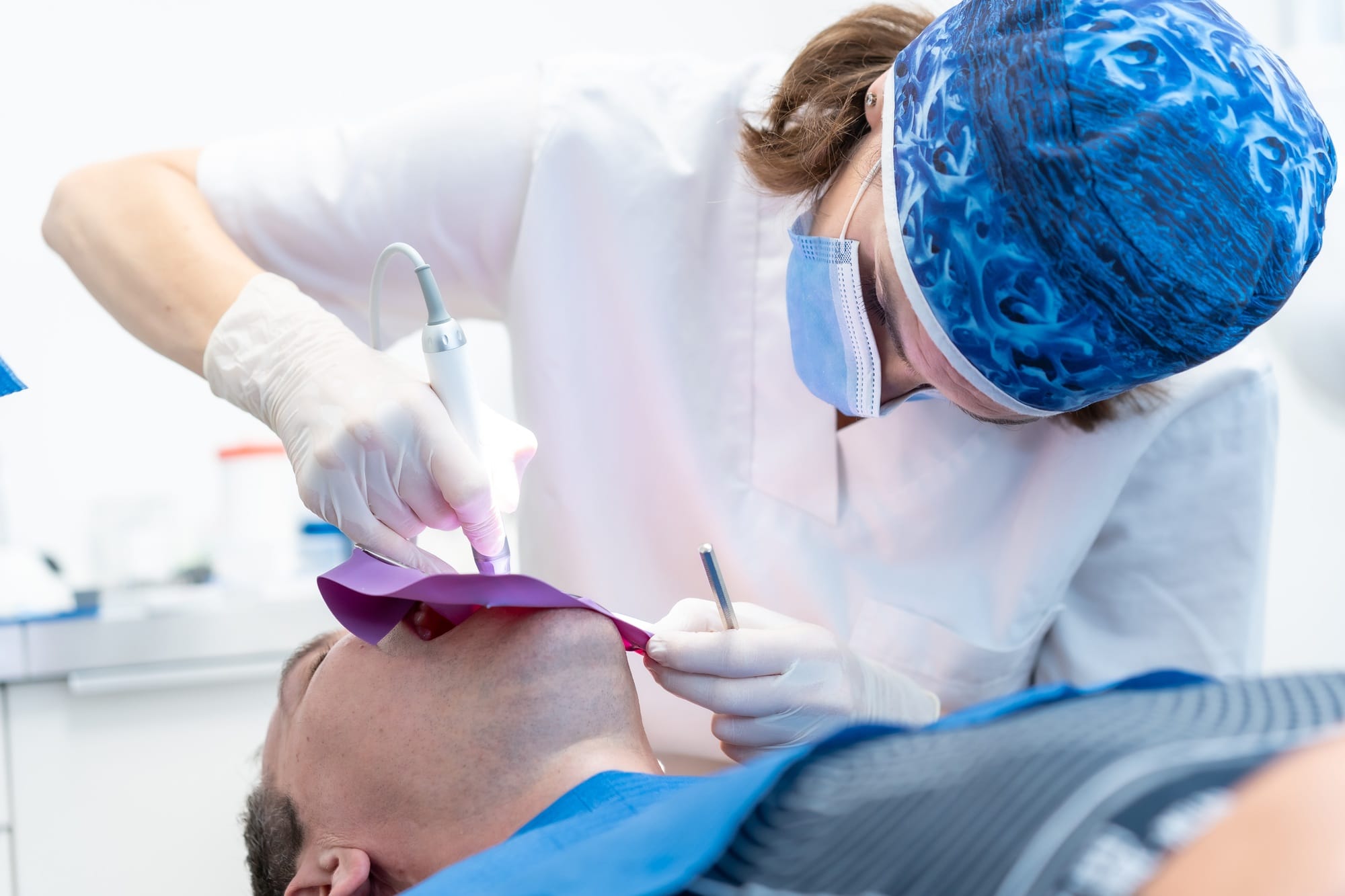 Dental clinic, a doctor performing a root canal to a patient in full operation Dental clinic, a doctor performing a root canal to a patient in full operation