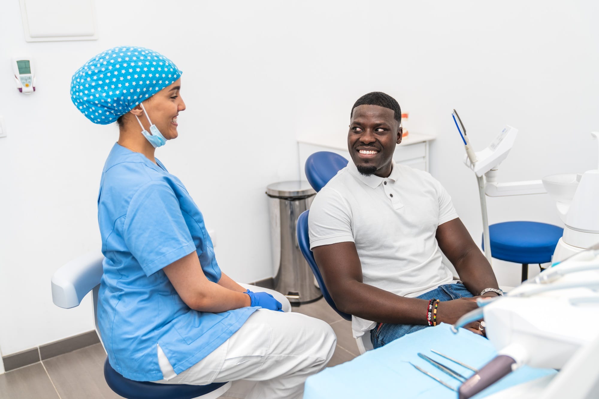 Dental hygienist and African male patient having a pleasant conversation before dental treatment. Dental hygienist and African male patient having a pleasant conversation before dental treatment.