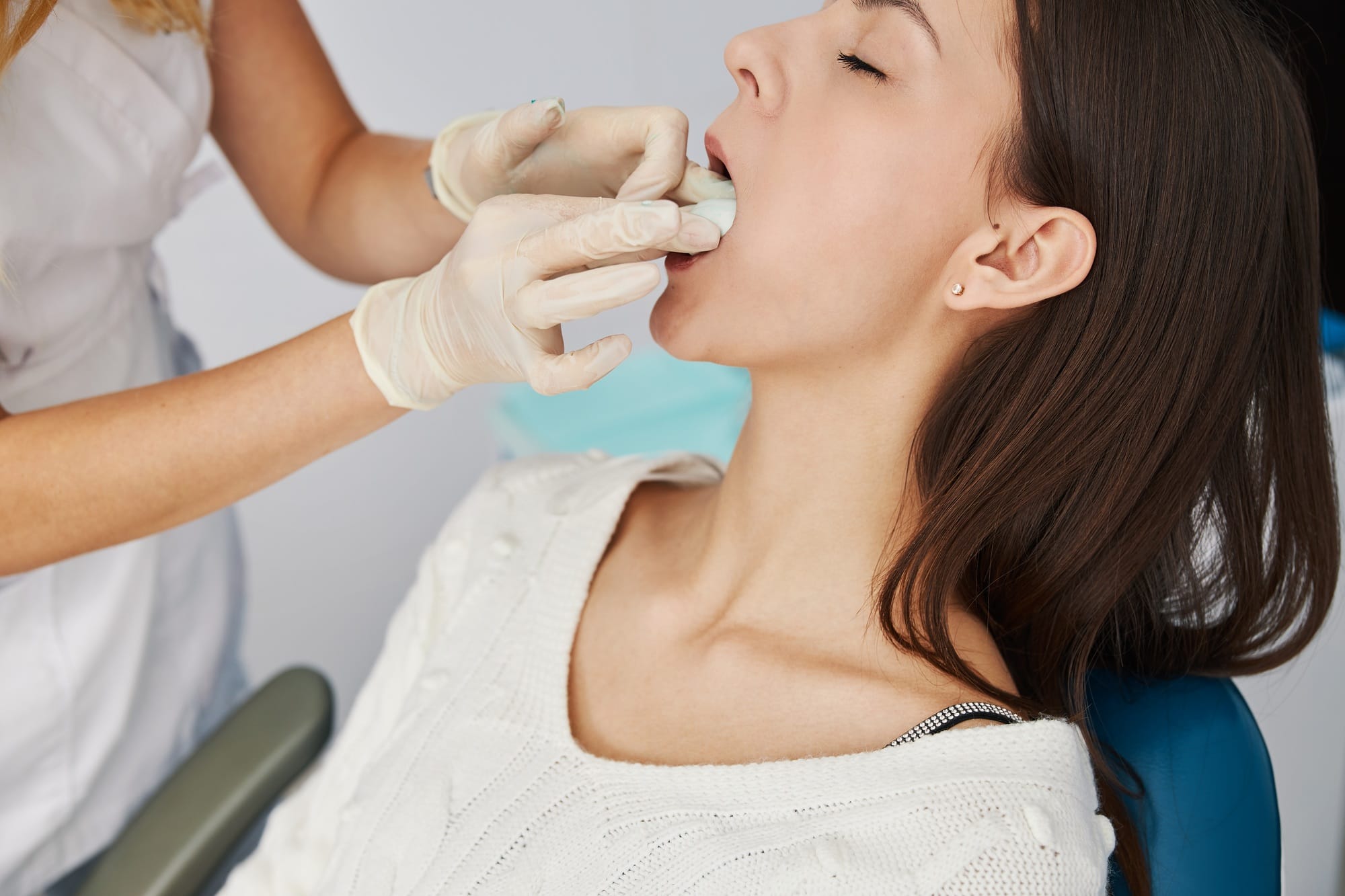 Dentist adjusting jaw cast putty lying on female tongue Dentist adjusting jaw cast putty lying on female tongue
