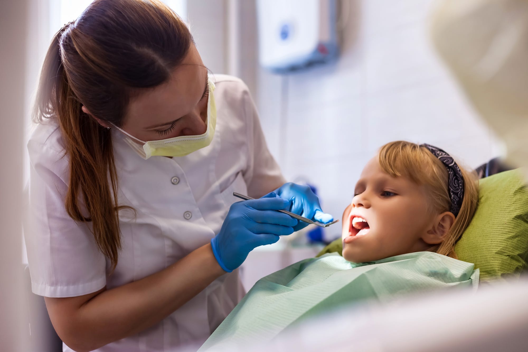 Dentist doing teeth checkup at dental office for adorable girl in children dentistry