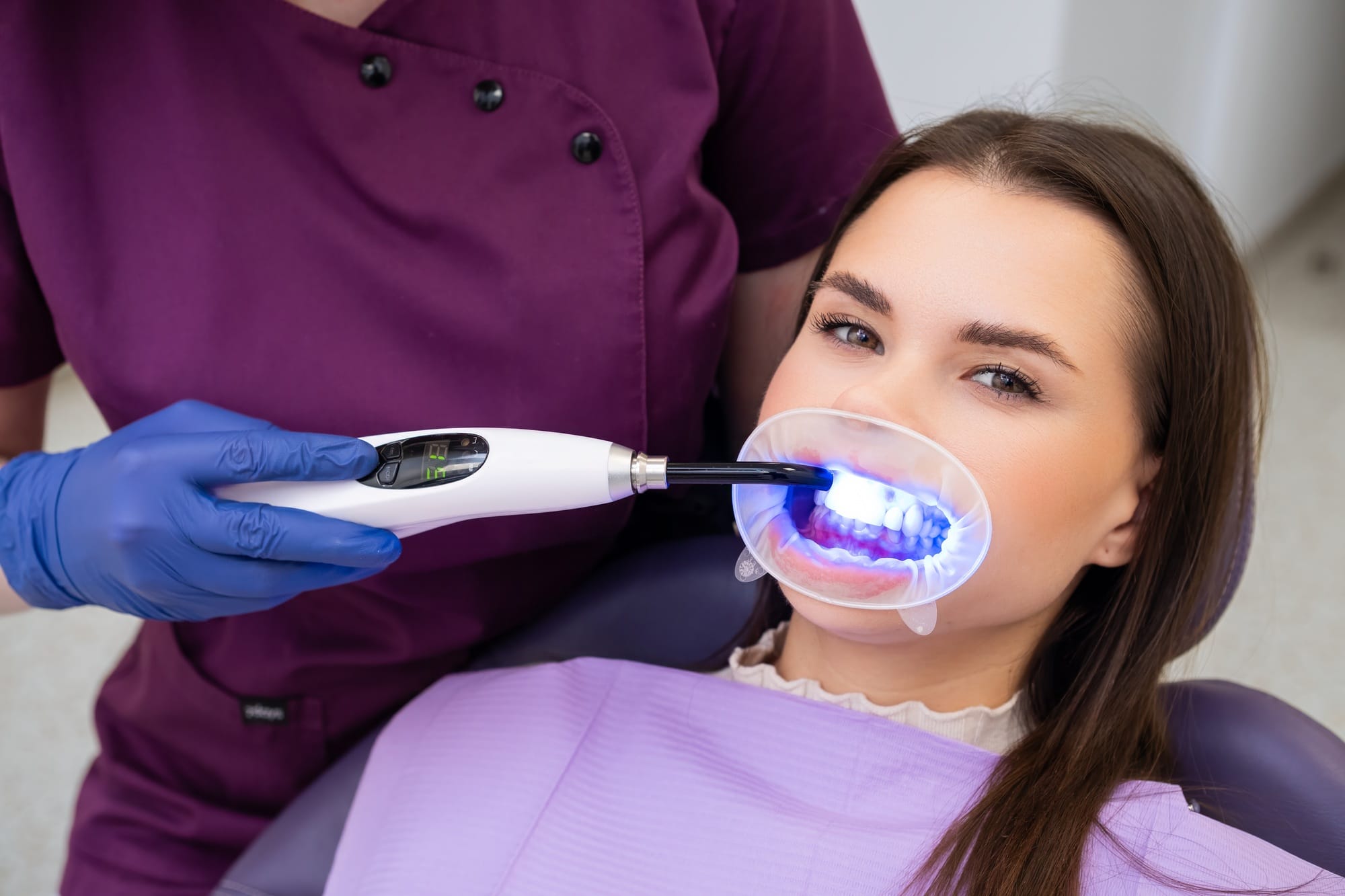 Dentist employs a UV lamp to cure the fillings in the patients teeth Dentist employs a UV lamp to cure the fillings in the patients teeth