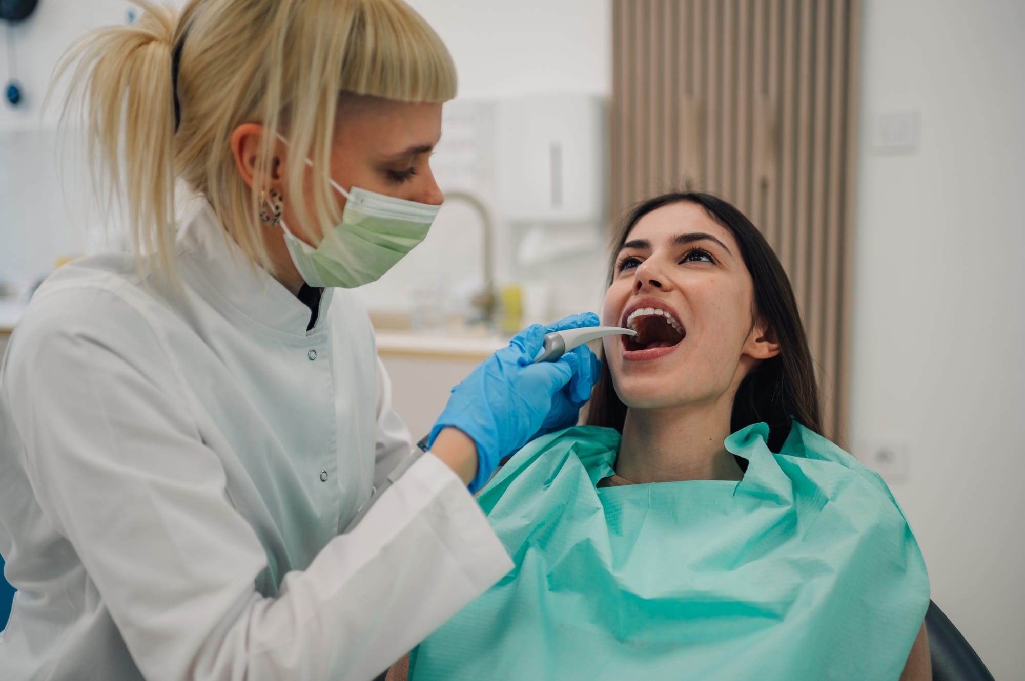 Dentist examining patient's teeth with dental intraoral camera in clinic