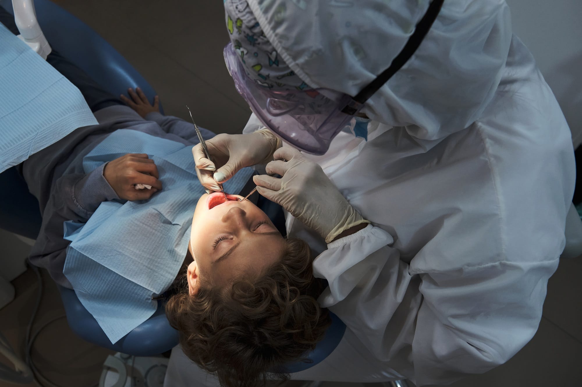 Dentist examining teeth of kid with tools in dental office Dentist examining teeth of kid with tools in dental office