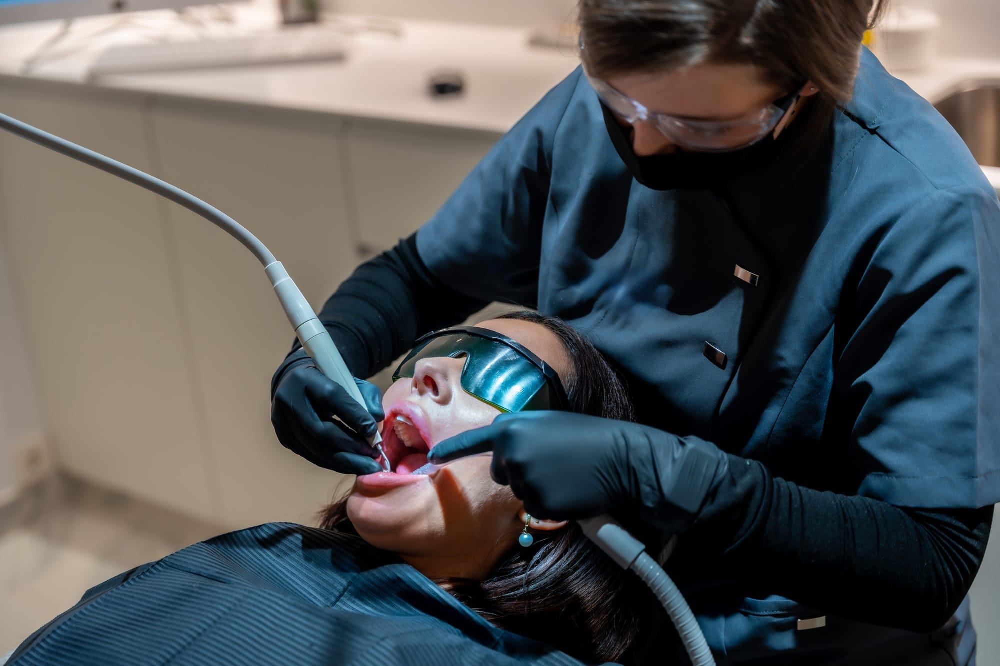 Dentist performing laser teeth whitening procedure on patient