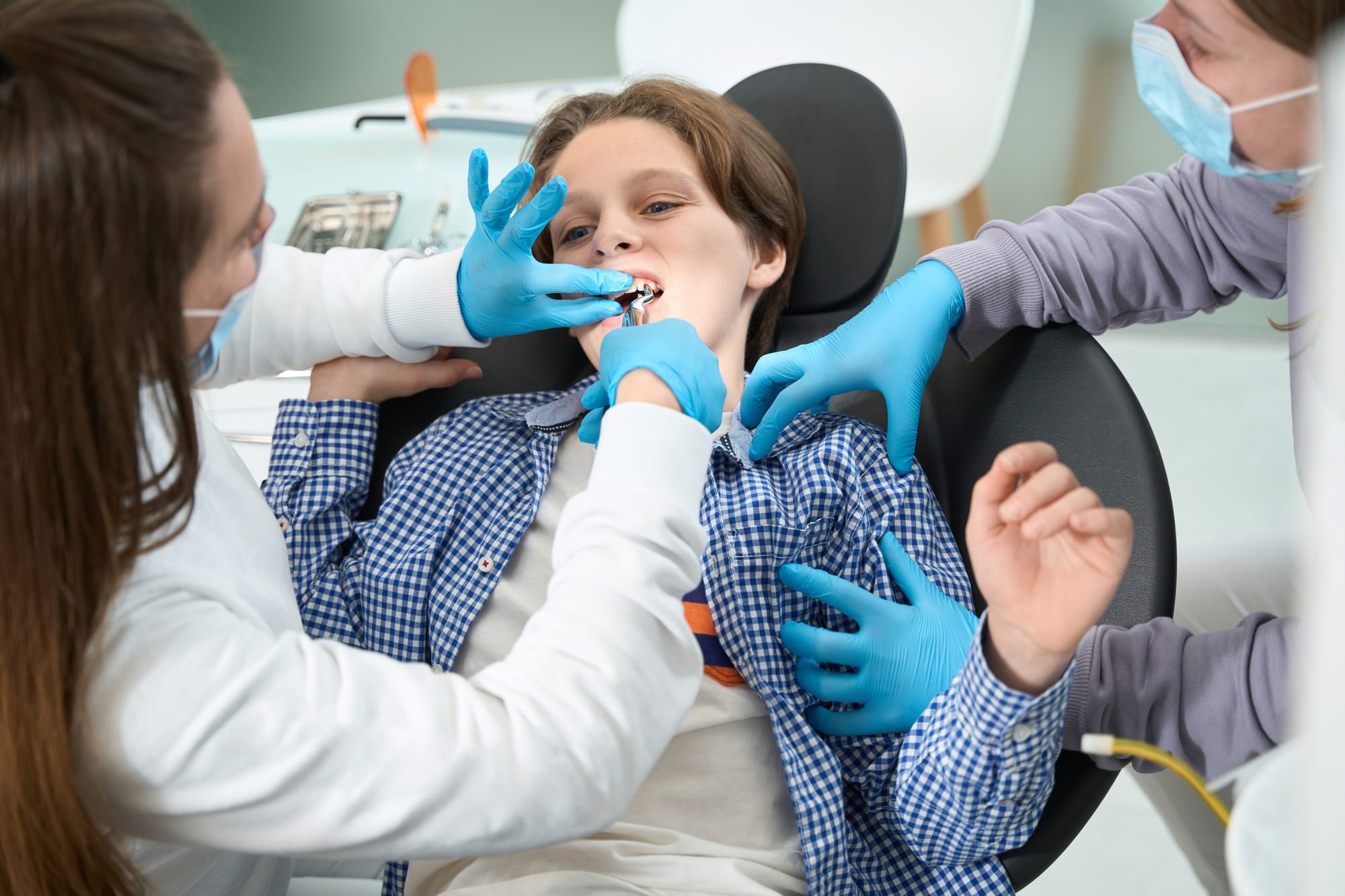 Dentist-surgeon removes a tooth to a teenager with special tool Dentist-surgeon removes a tooth to a teenager with special tool