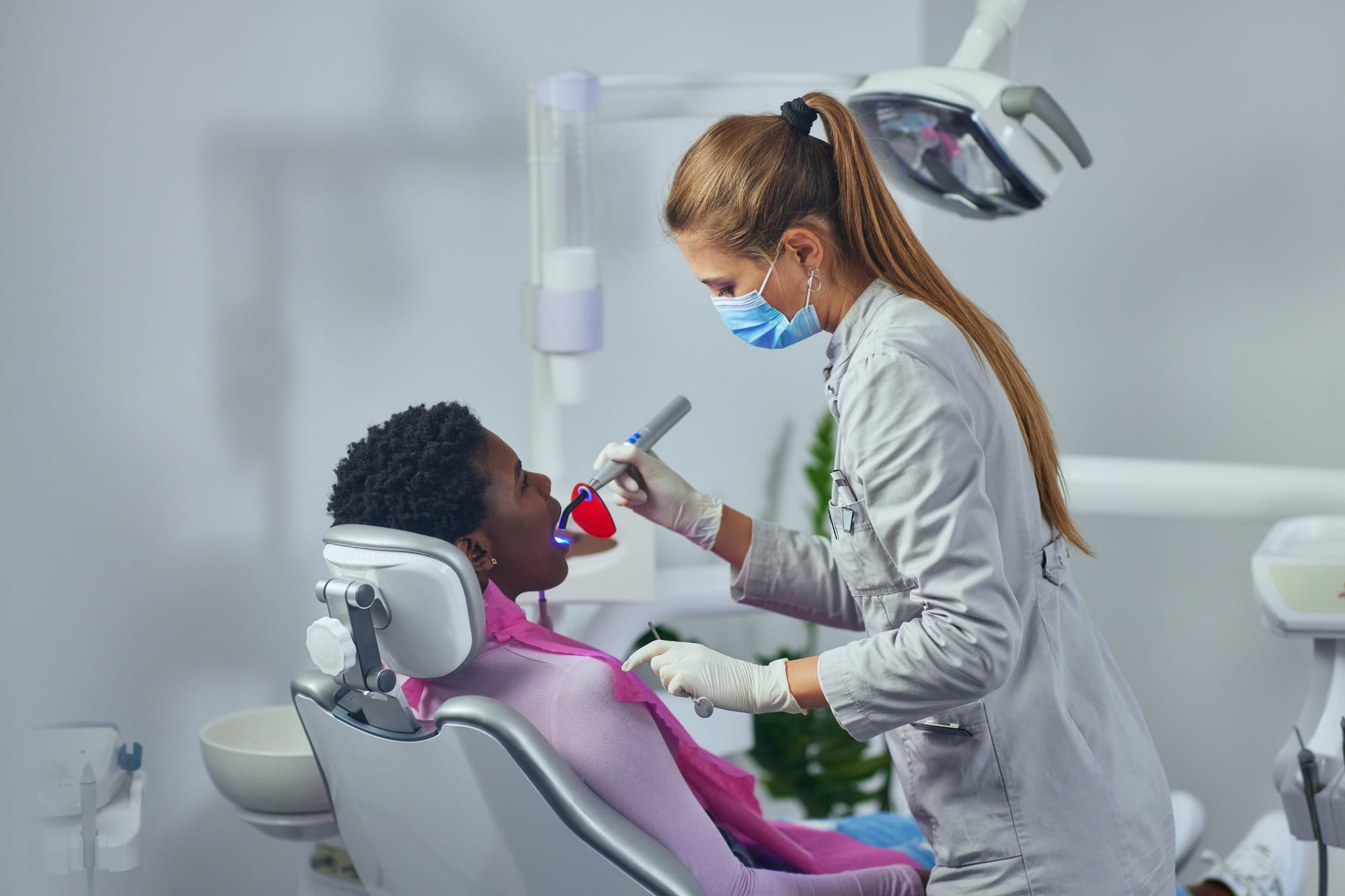 Dentist with face mask checking patient's teeth Dentist with face mask checking patient's teeth