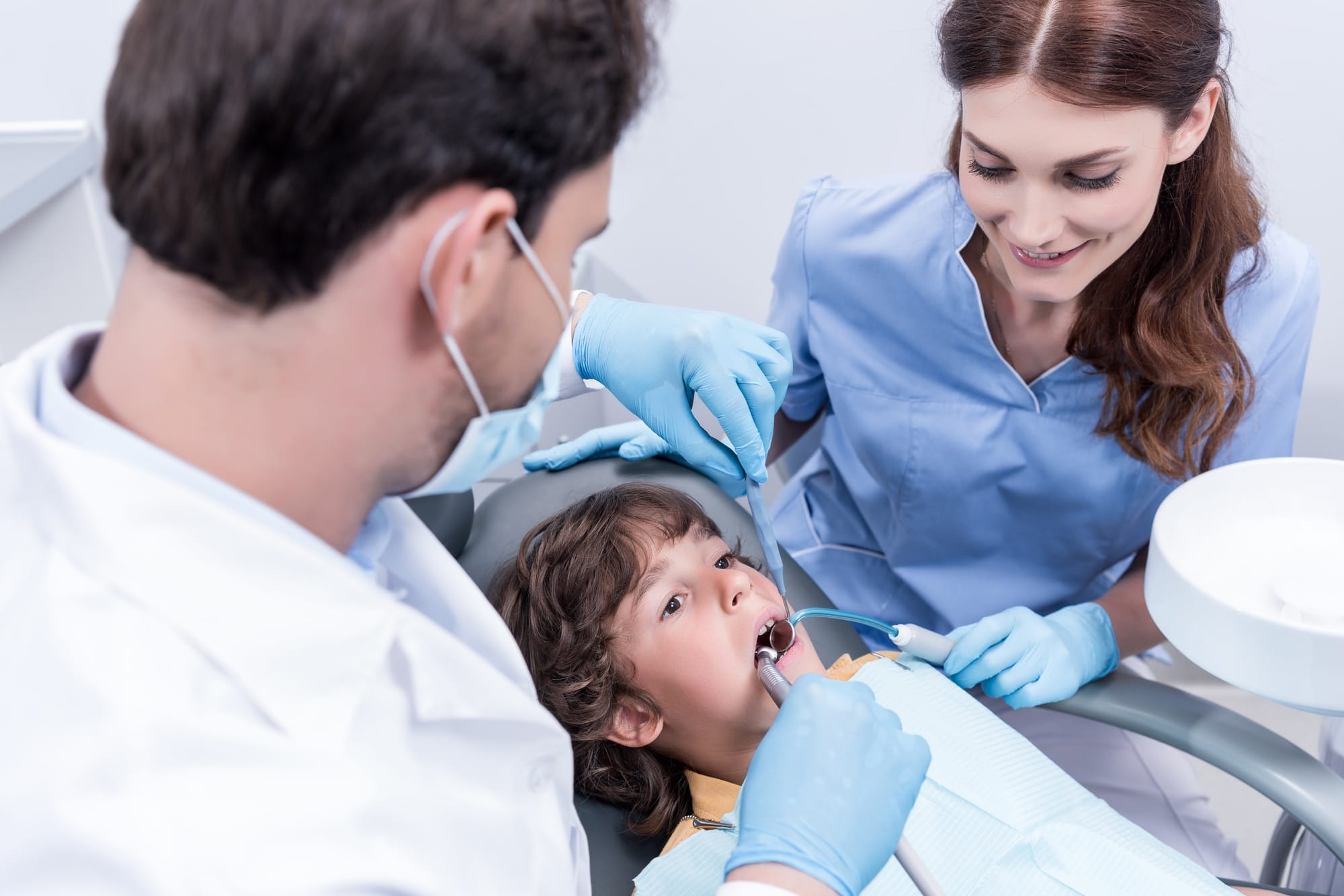 dentists treating teeth of little patient in dentist chair in hospital dentists treating teeth of little patient in dentist chair in hospital