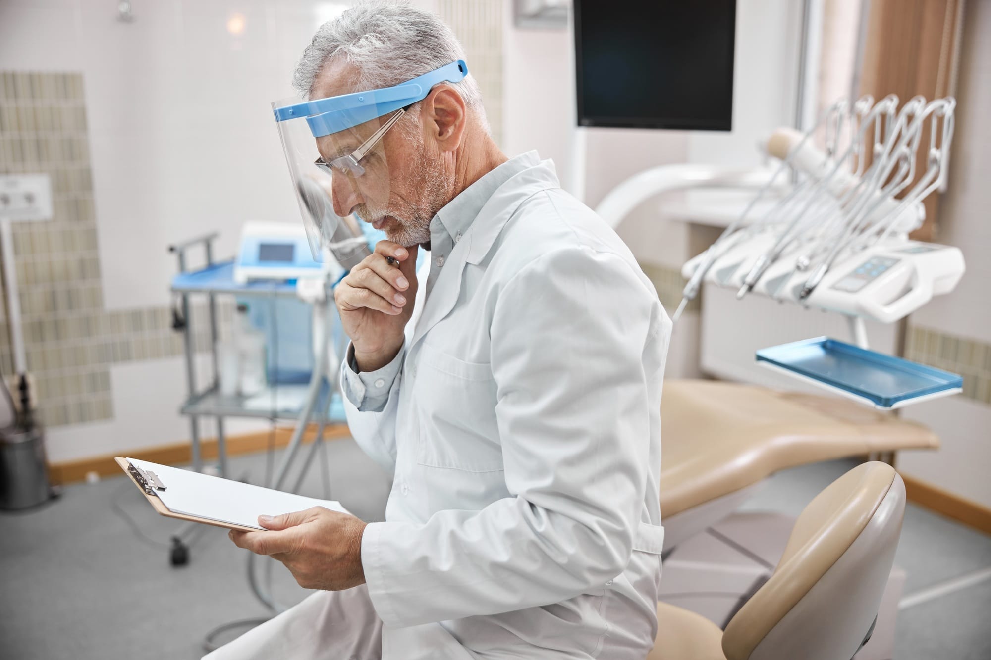 Elderly dentist checking his schedule of appointments Elderly dentist checking his schedule of appointments