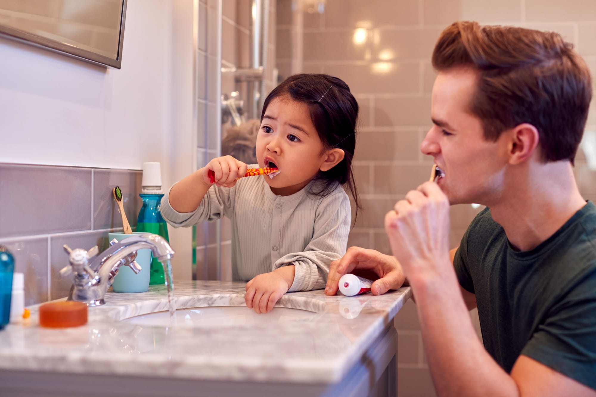 Family With Dad And Daughter Brushing Teeth In Bathroom At Home Together Family With Dad And Daughter Brushing Teeth In Bathroom At Home Together