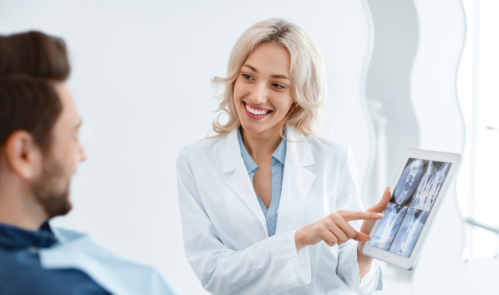 Female dentist showing male patient x-ray on digital tablet Female dentist showing male patient x-ray on digital tablet