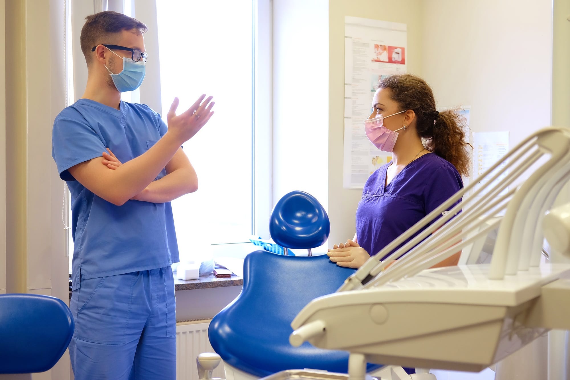 Handsome male dentist speaks with a female assistant at a clinic.