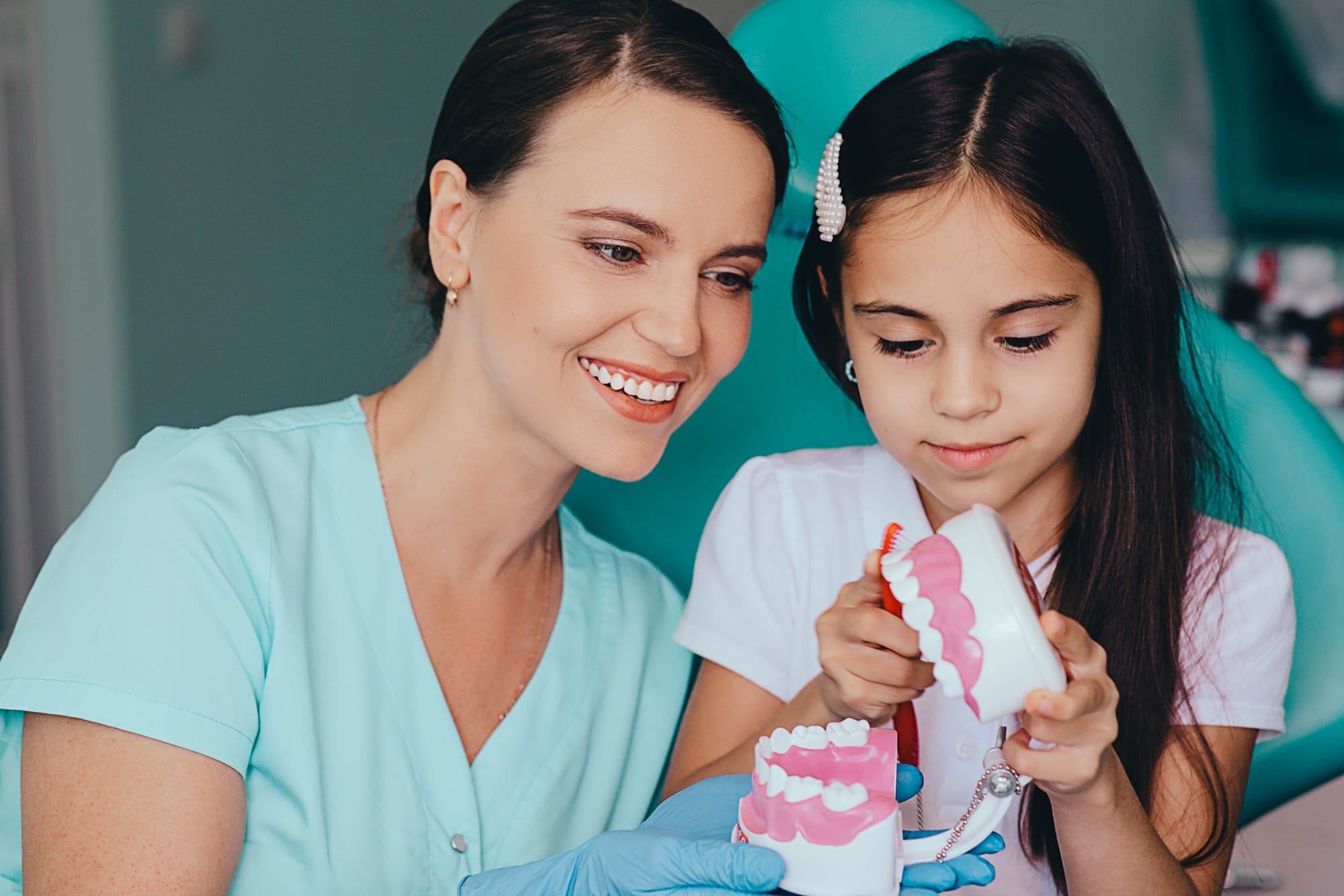 Little girl and pediatric dentist at dental clinic. Dentist having fun with little patient Little girl and pediatric dentist at dental clinic. Dentist having fun with little patient