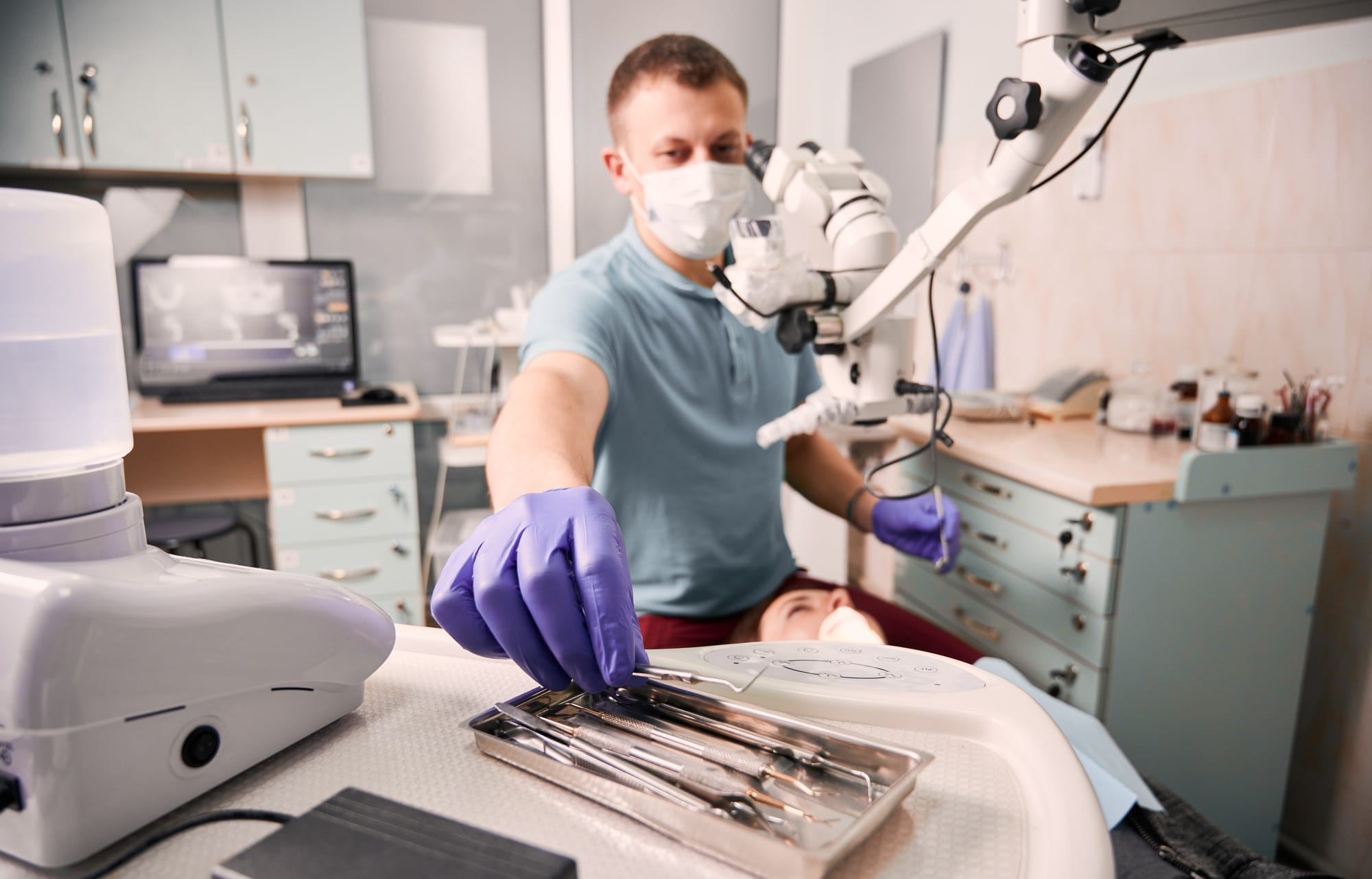 Male dentist grabbing dental explorer during dental procedure. Male dentist grabbing dental explorer during dental procedure.