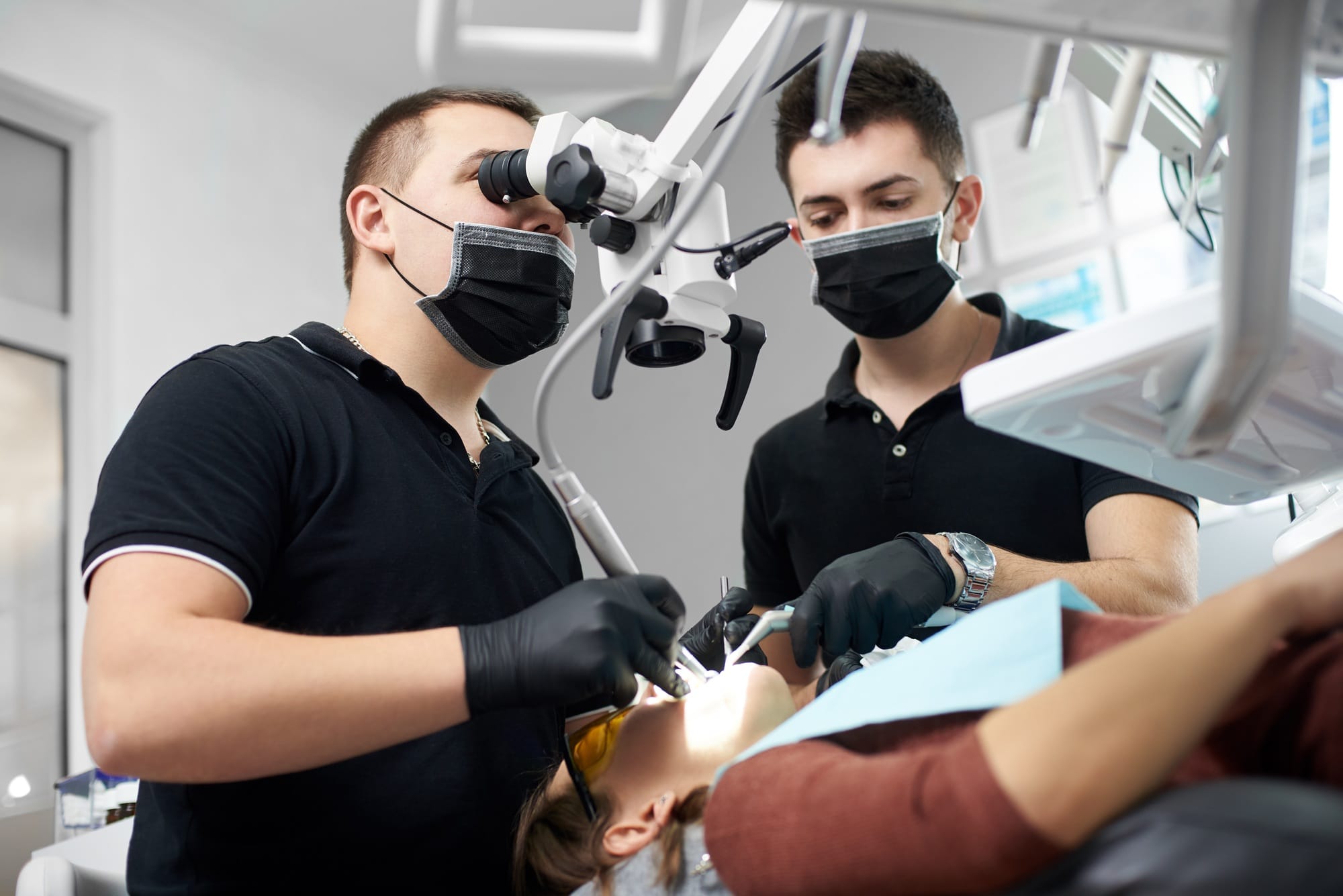 Male dentist in a black uniform fixing patient's teeth Male dentist in a black uniform fixing patient's teeth