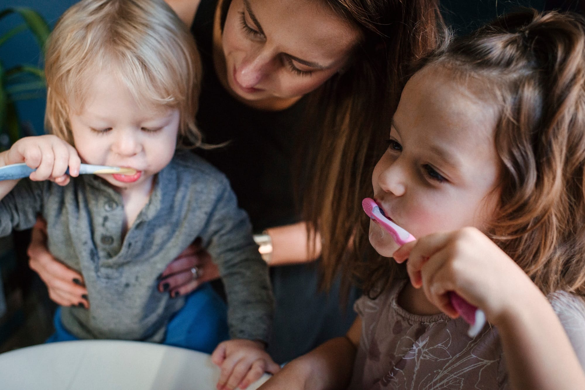 Mother helping children brush teeth Mother helping children brush teeth