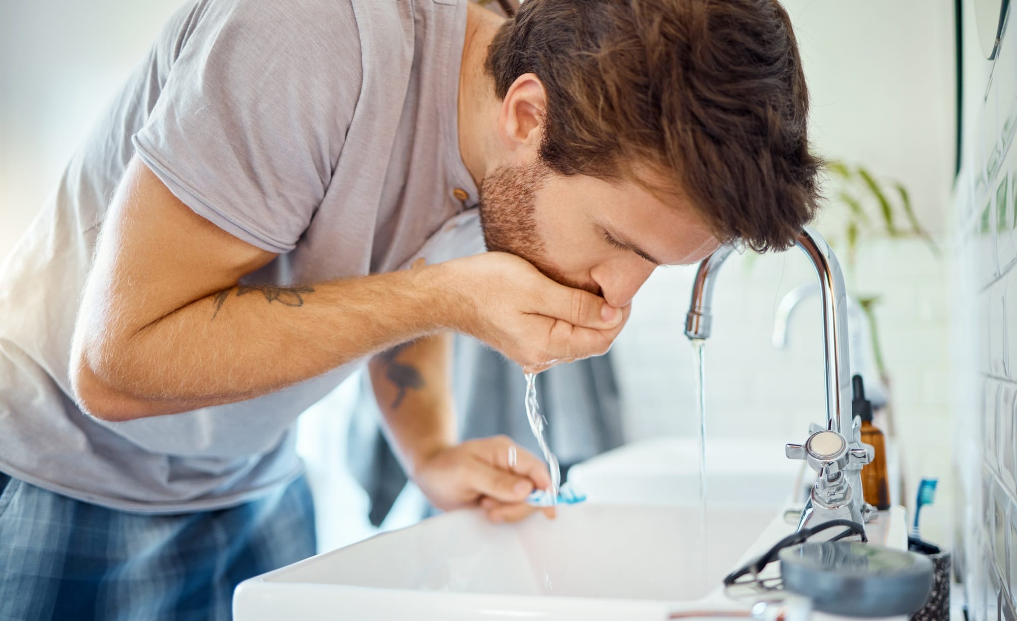 One handsome man rinsing his mouth in a bathroom at home. Caucasian male using mouthwash for fresh One handsome man rinsing his mouth in a bathroom at home. Caucasian male using mouthwash for fresh