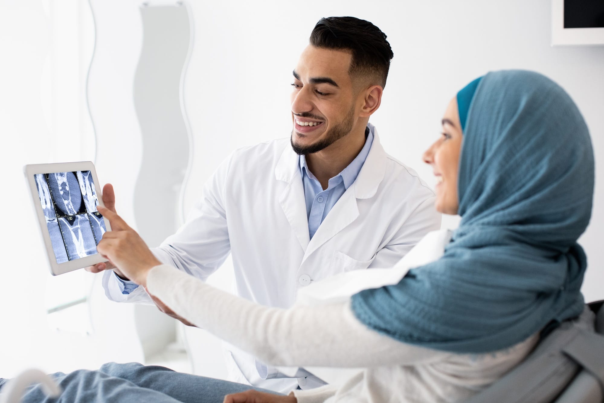 Orthodontist Doctor Showing Teeth Xray On Digital Tablet To Muslim Female Patient Orthodontist Doctor Showing Teeth Xray On Digital Tablet To Muslim Female Patient