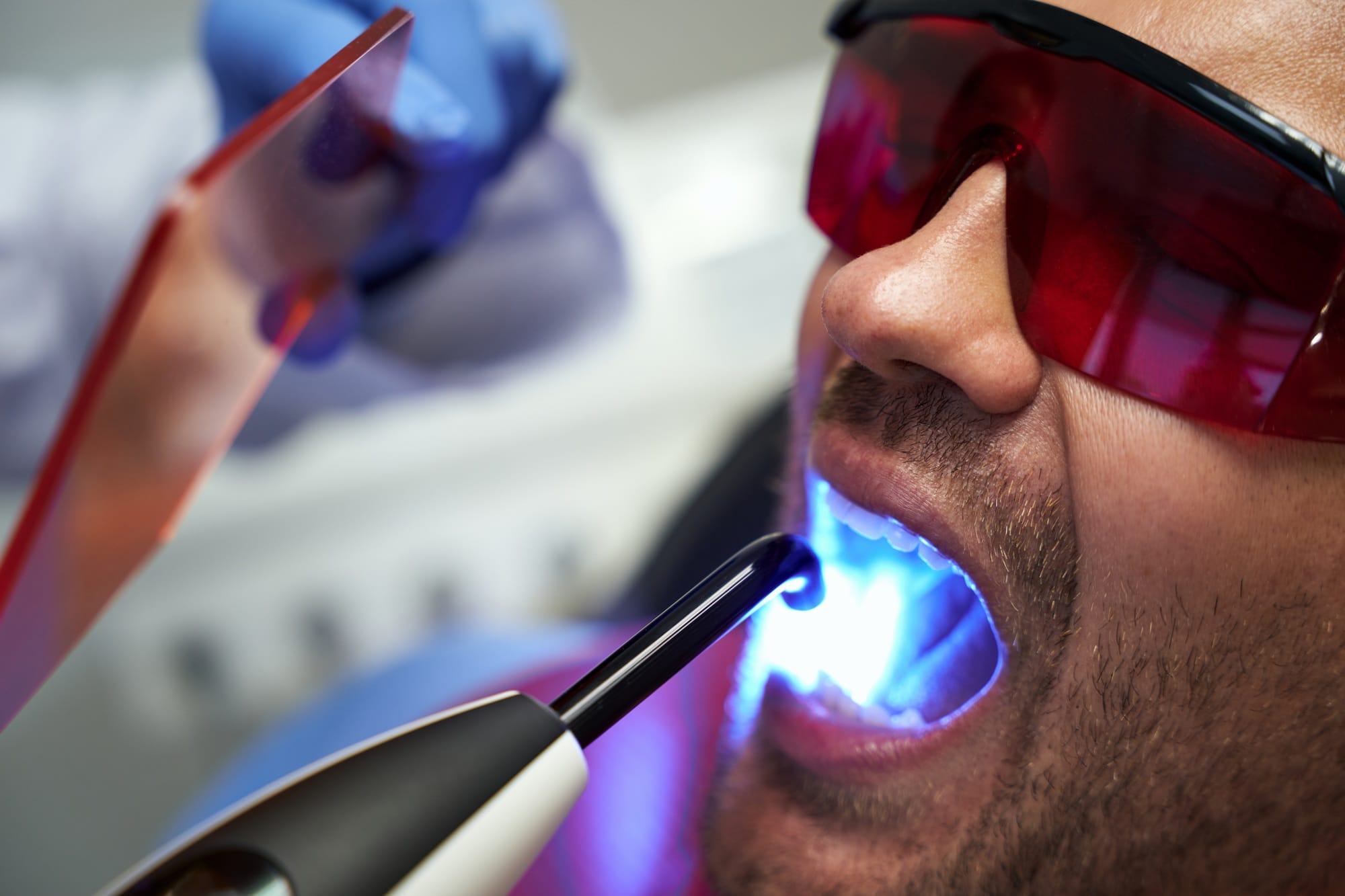 Patient in glasses receiving laser dental treatment at clinic Patient in glasses receiving laser dental treatment at clinic