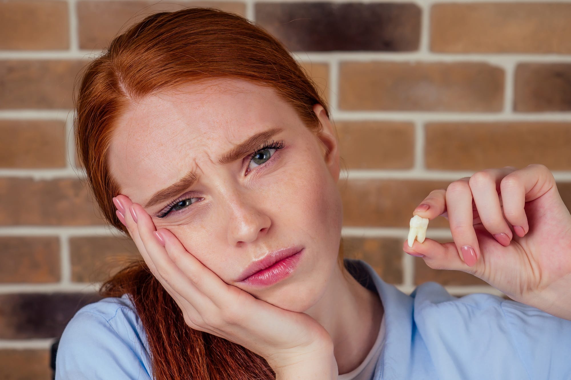 redhaired ginger female with pain grimace holding white wisdom tooth Stomatological dental equipment, dentist whitening filling tooth of patient at dental hospital
