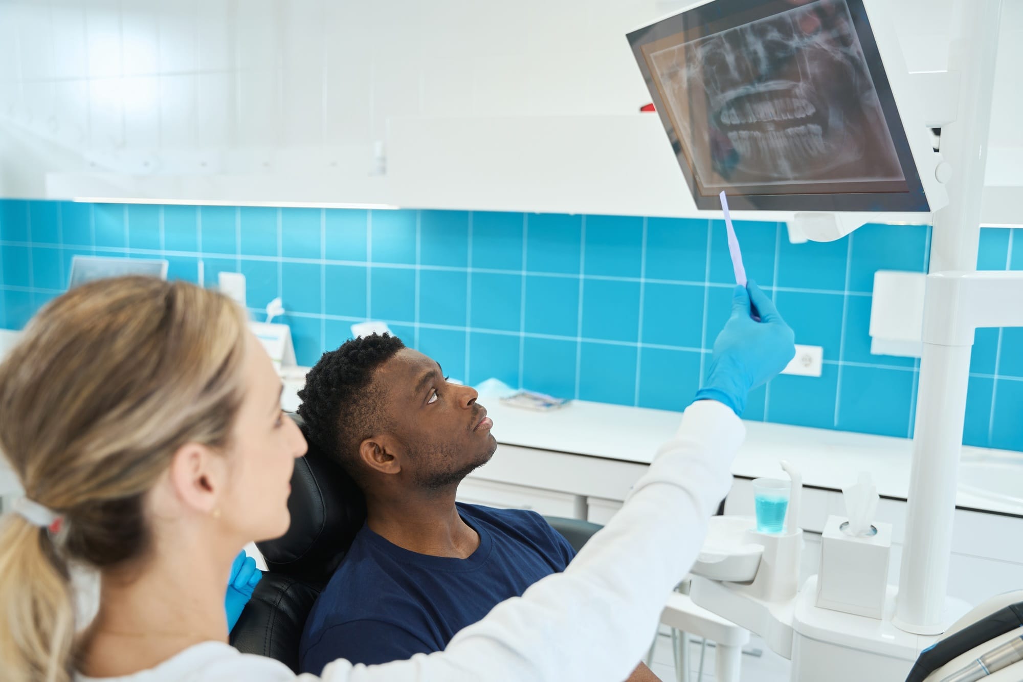 Stomatologist showing to client digital screen with x-ray image of his jaw Stomatologist showing to client digital screen with x-ray image of his jaw