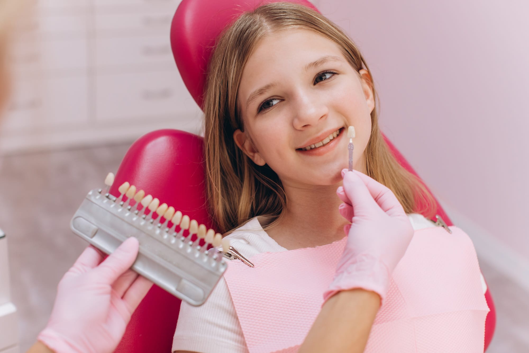 The dentist selects the color of the dental crown of a teenage girl in a dental clinic The dentist selects the color of the dental crown of a teenage girl in a dental clinic