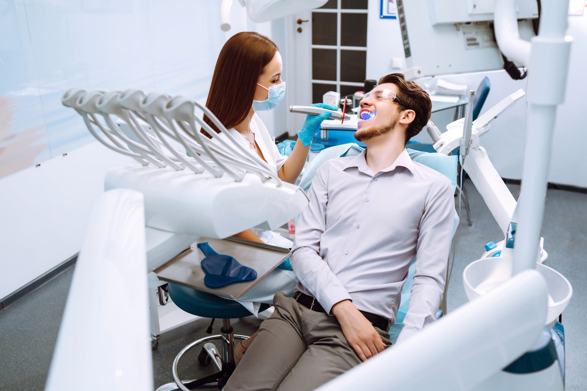 Young man at the dentist's chair during a dental procedure. Overview of dental caries prevention. Young man at the dentist's chair during a dental procedure. Overview of dental caries prevention.
