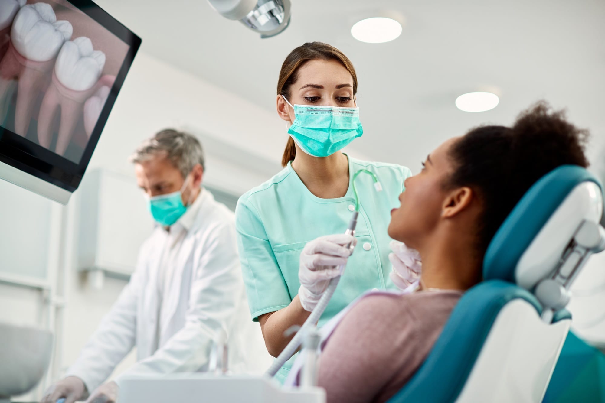 Young nurse preparing patient for dental procedure at dentist's office. Young nurse preparing patient for dental procedure at dentist's office.