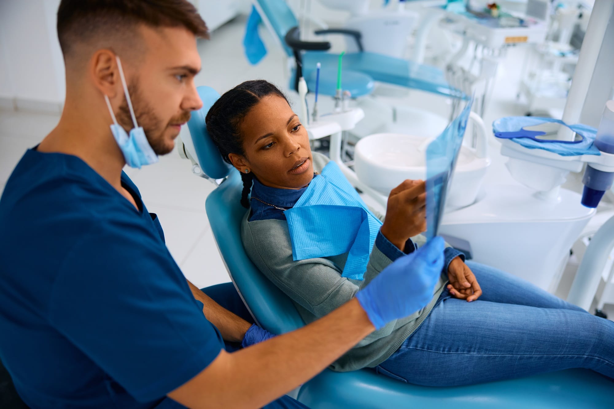 Black woman and her dentist examining dental X-ray during appointment at dental clinic. Black woman and her dentist examining dental X-ray during appointment at dental clinic.