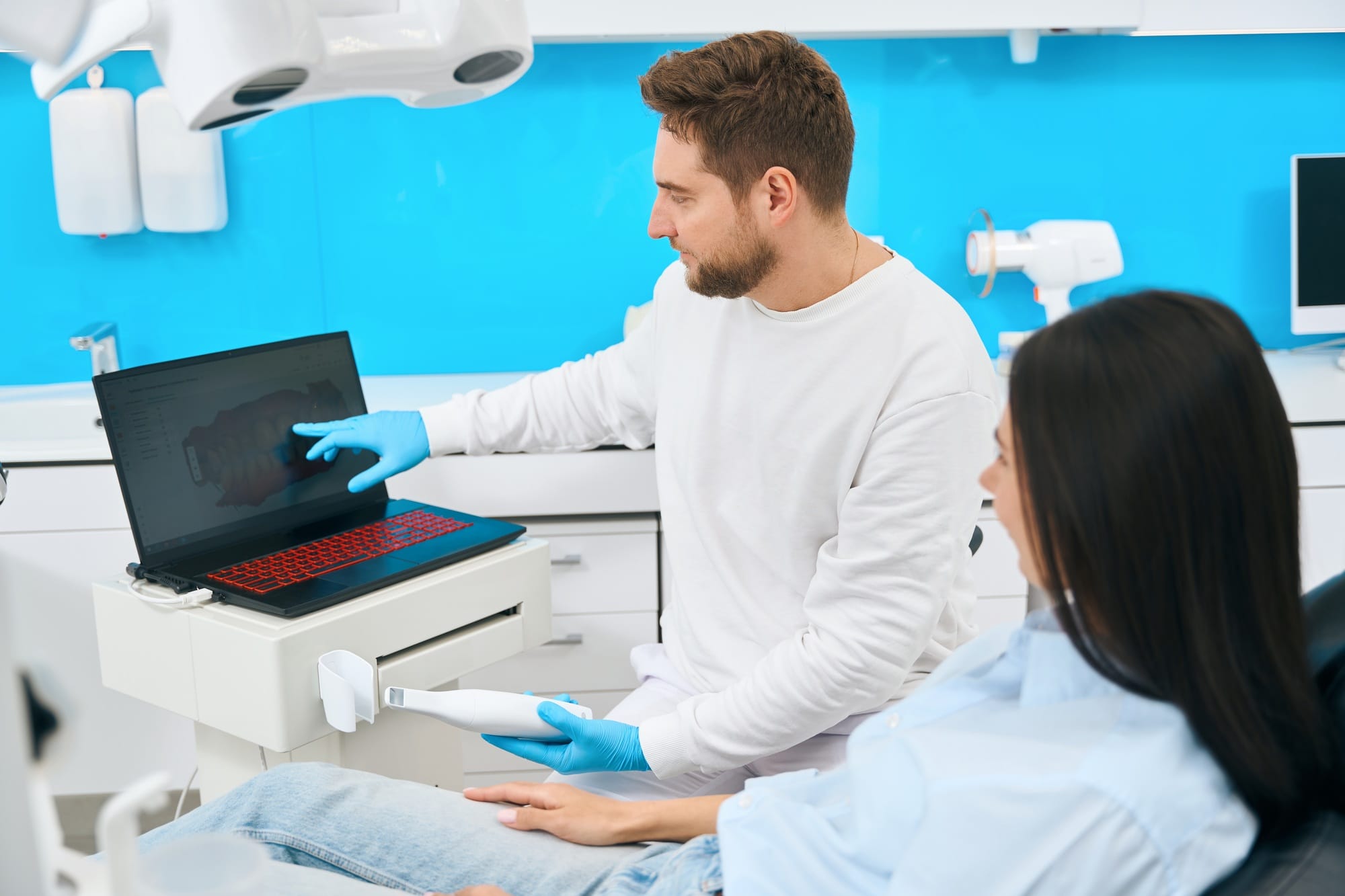 Dental technician showing at digital monitor problem teeth to female client