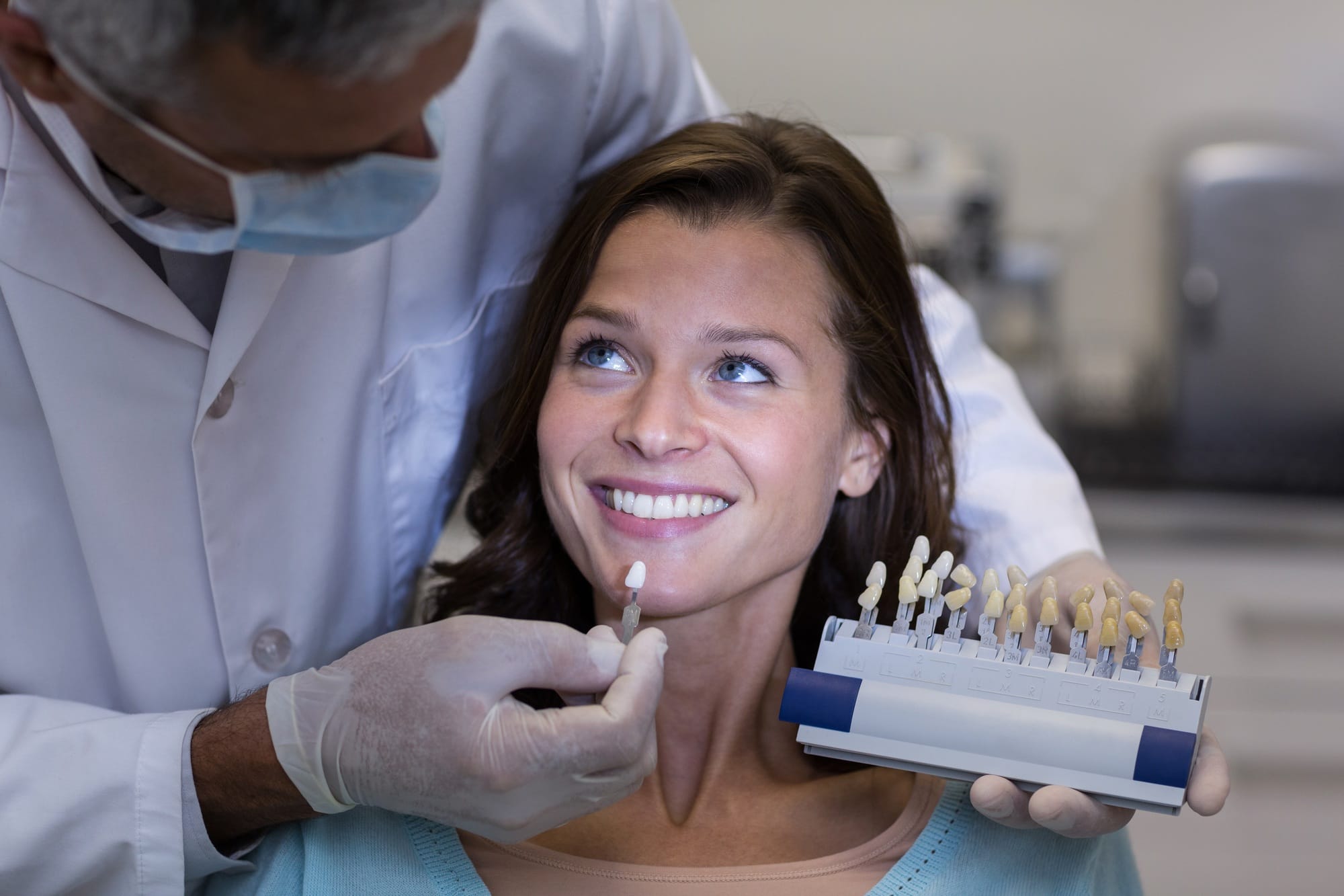 Dentist examining female patient with teeth shades Dentist examining female patient with teeth shades