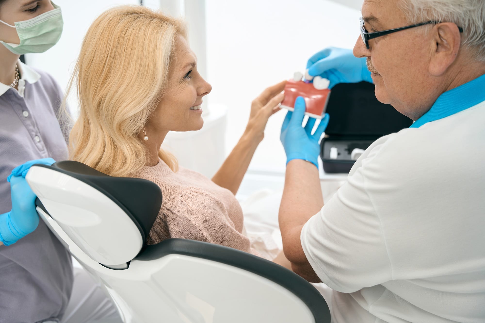 Dentist holding model of teeth with dental implant