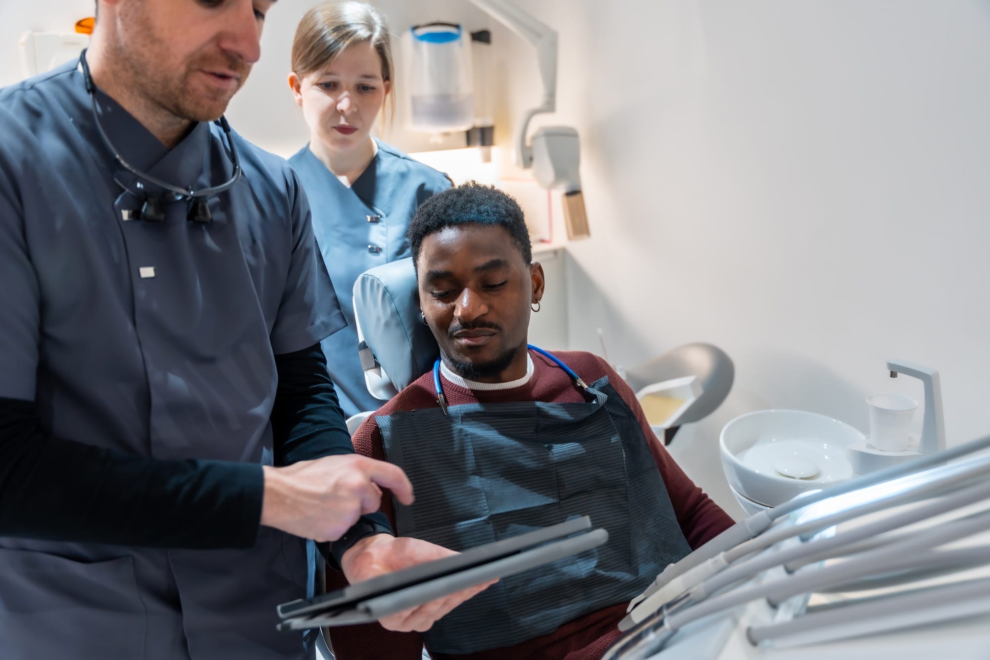 Dentist showing results on tablet to patient in dental clinic