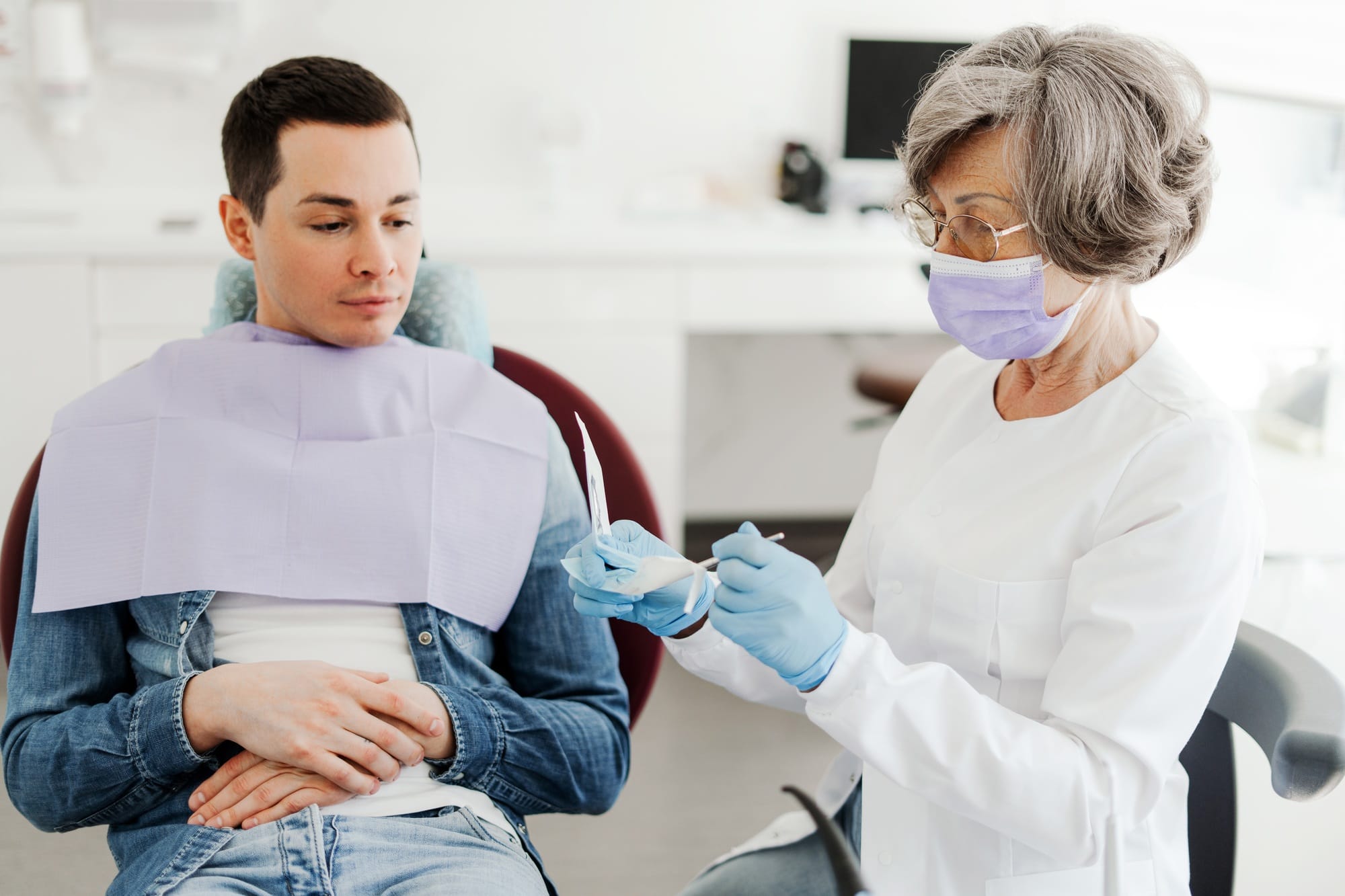 Experienced, senior dentist, attractive woman holding dental equipment, talking with patient