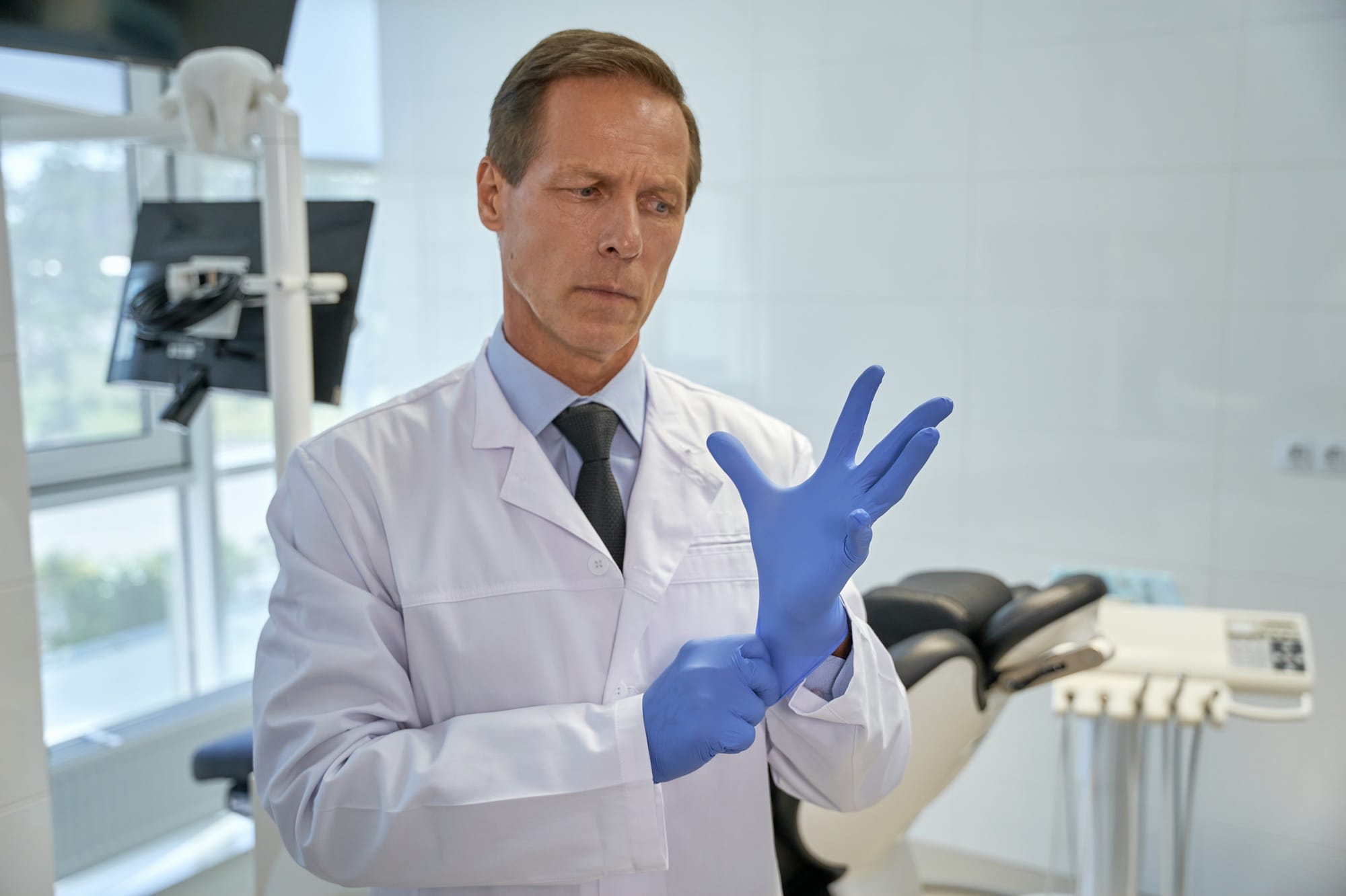 Puzzled dental specialist using disposable gloves at work Puzzled dental specialist using disposable gloves at work